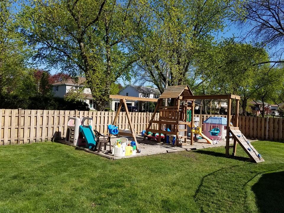 Wooden playground set with swings and slides in a grassy backyard