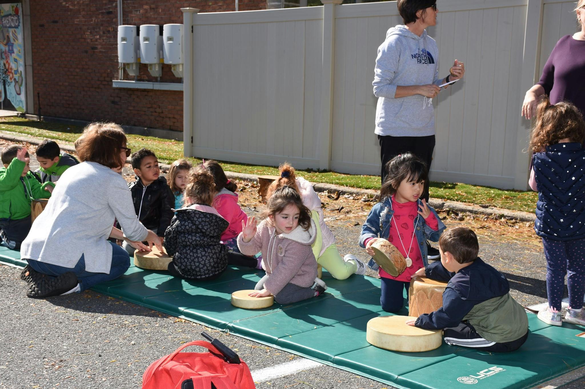 Adults and children sitting on mats outdoors