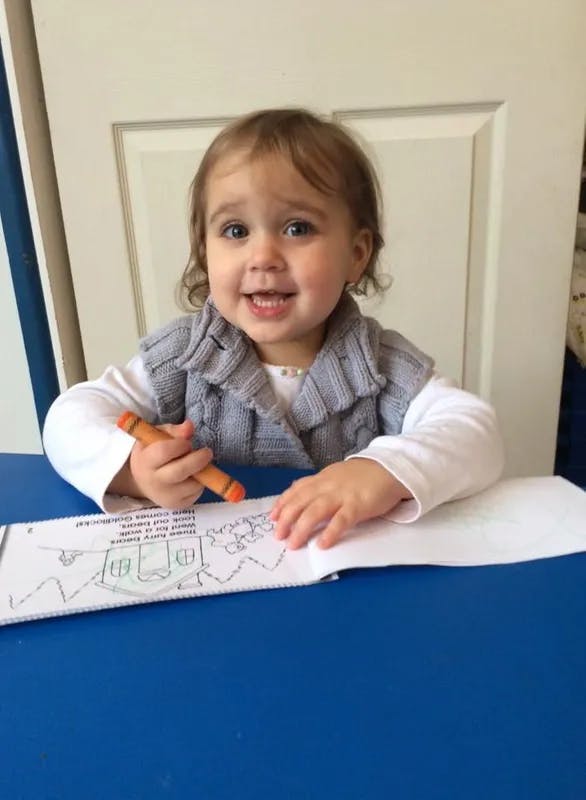 Child holding a crayon and coloring a picture