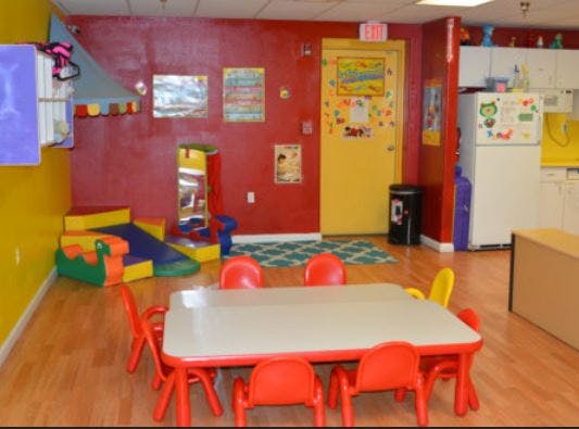 Playroom with a table and chairs, soft play equipment, and a yellow door