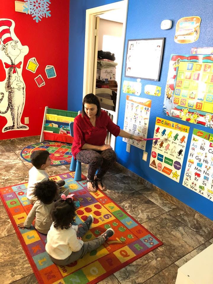 Person teaching three children in a classroom