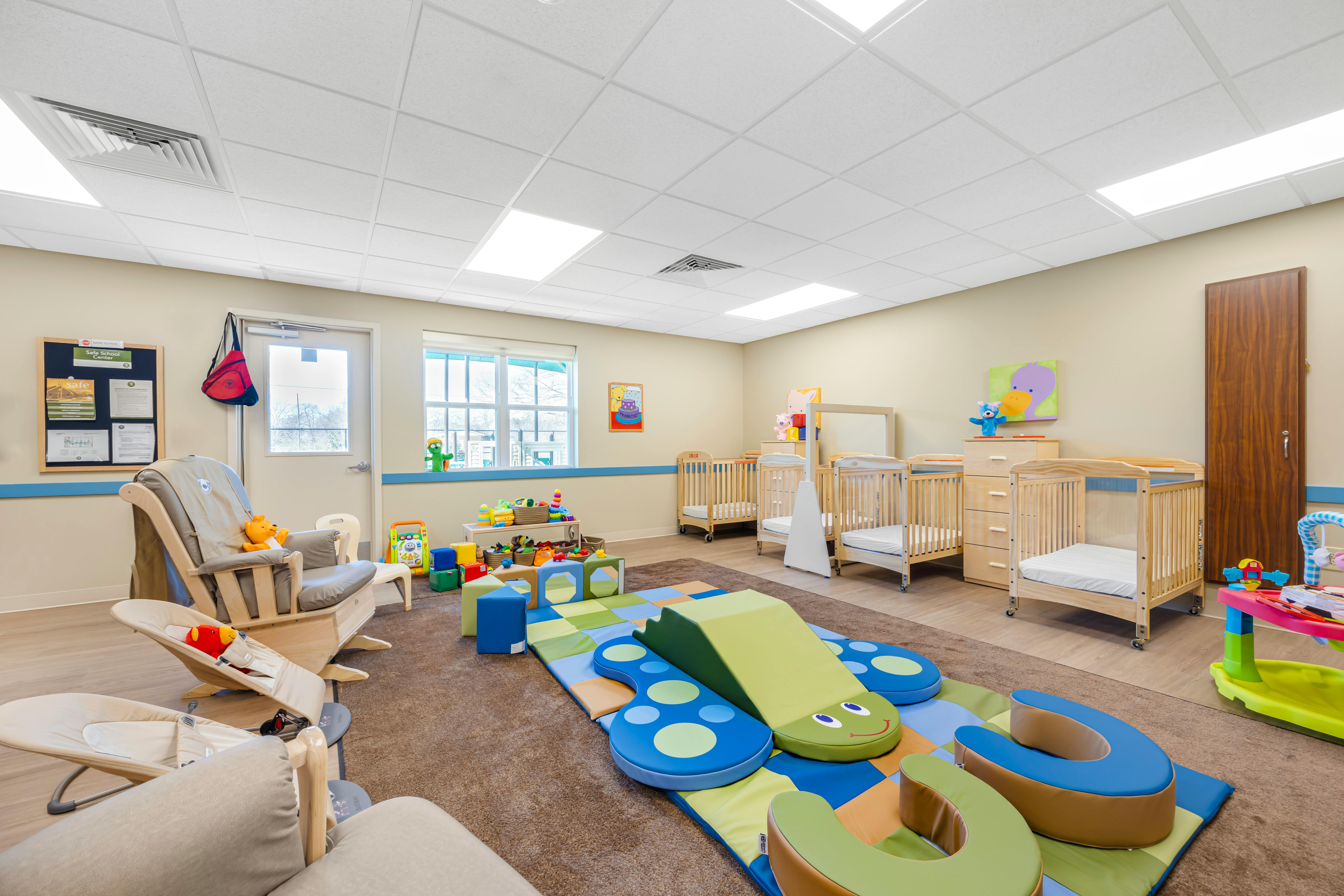 Baby room with multiple cribs, a rocking chair, and soft play equipment