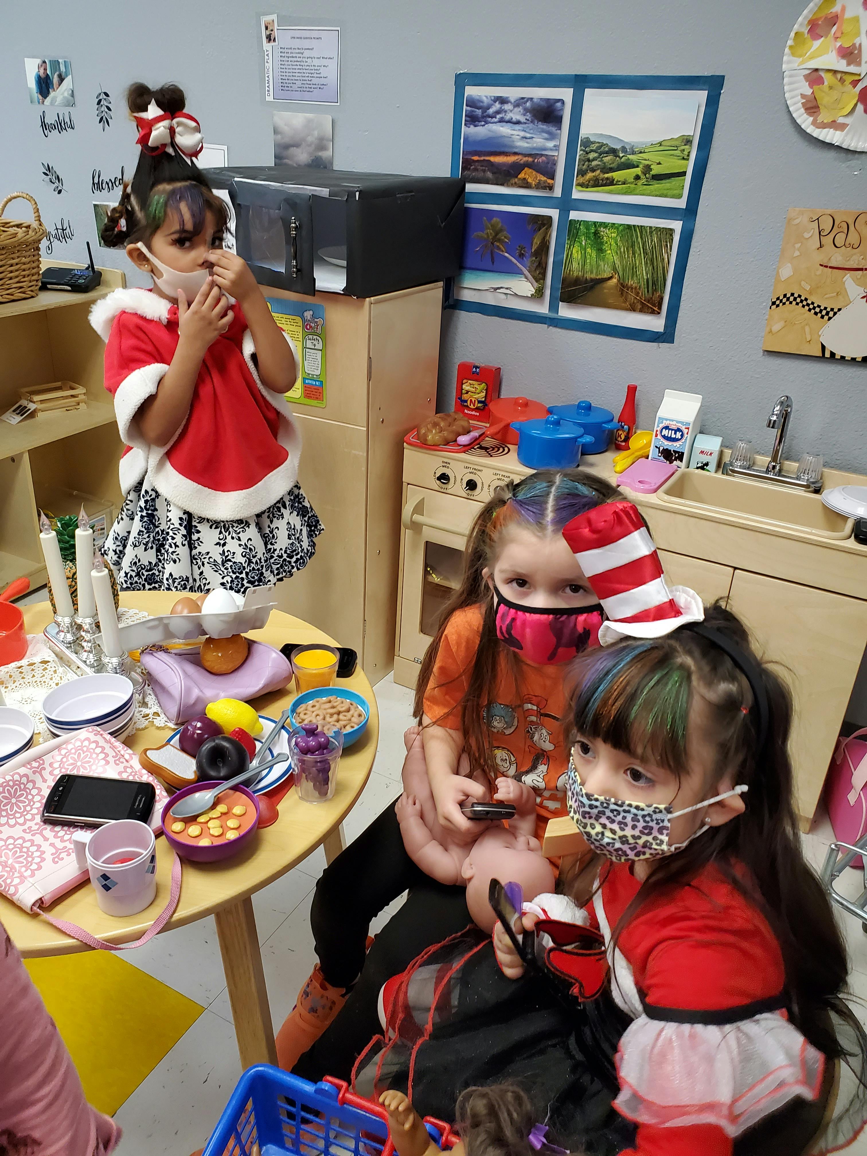 Three children wearing masks playing in a classroom