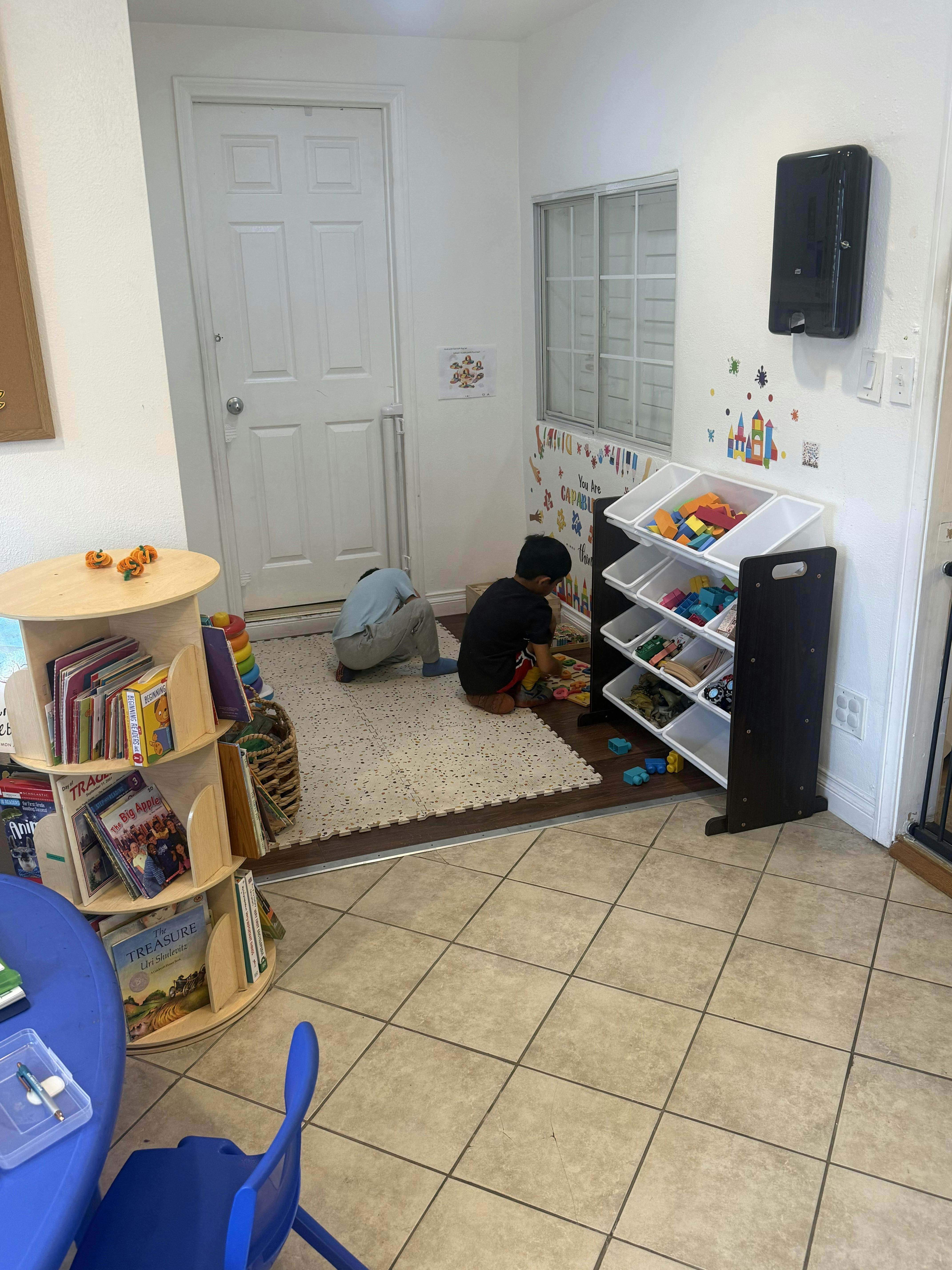 Two children playing with toys on a mat in a classroom