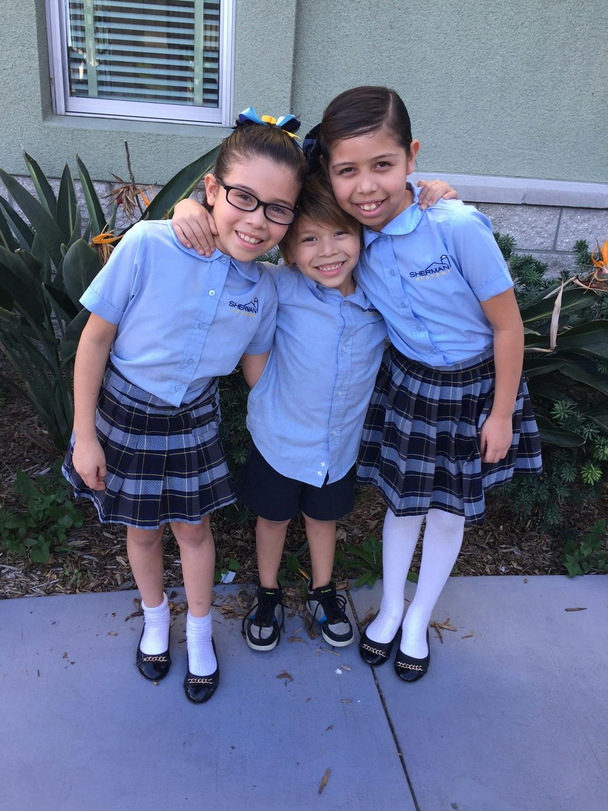Three children in school uniforms posing together