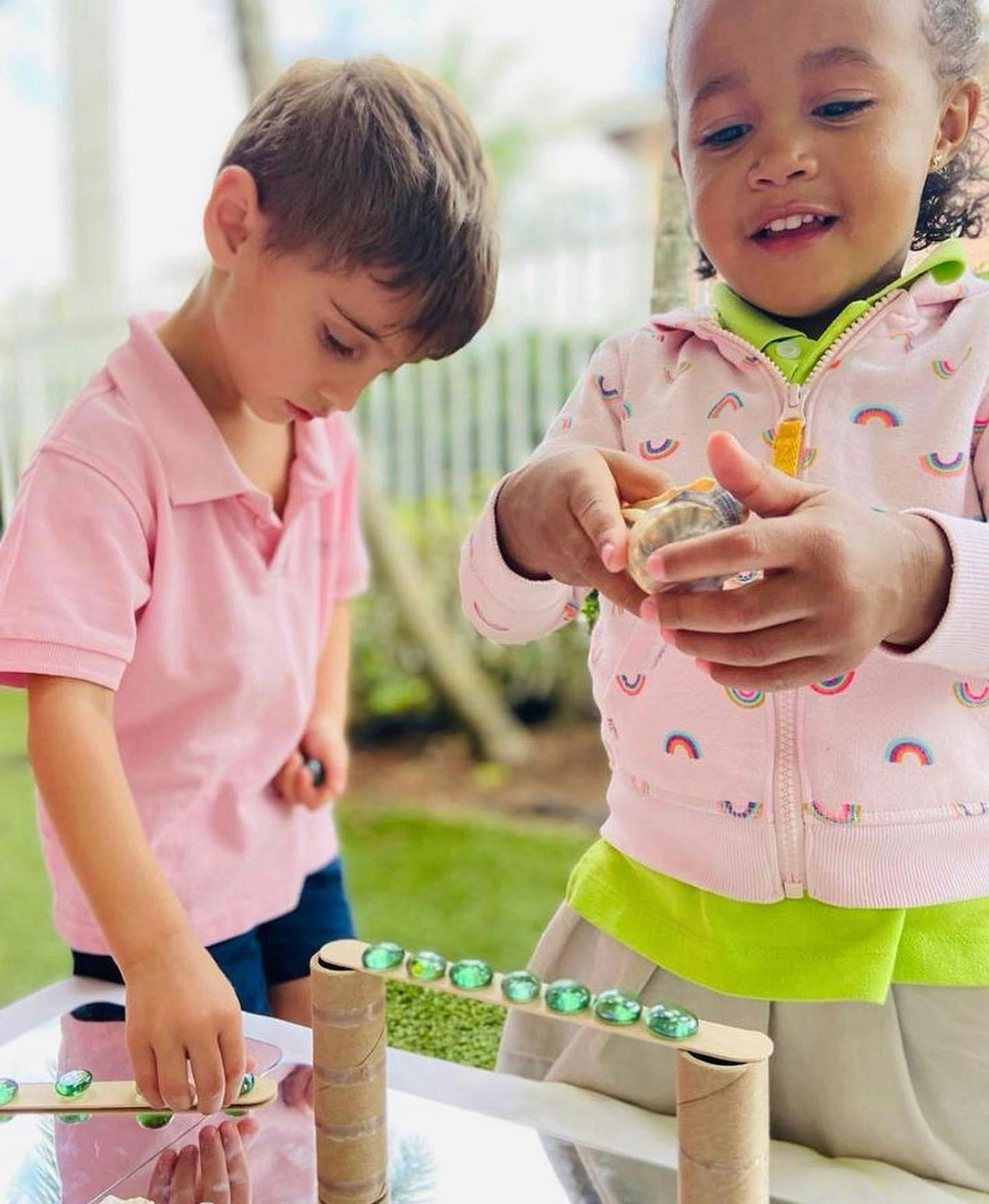 Two children playing with marbles on a homemade ramp