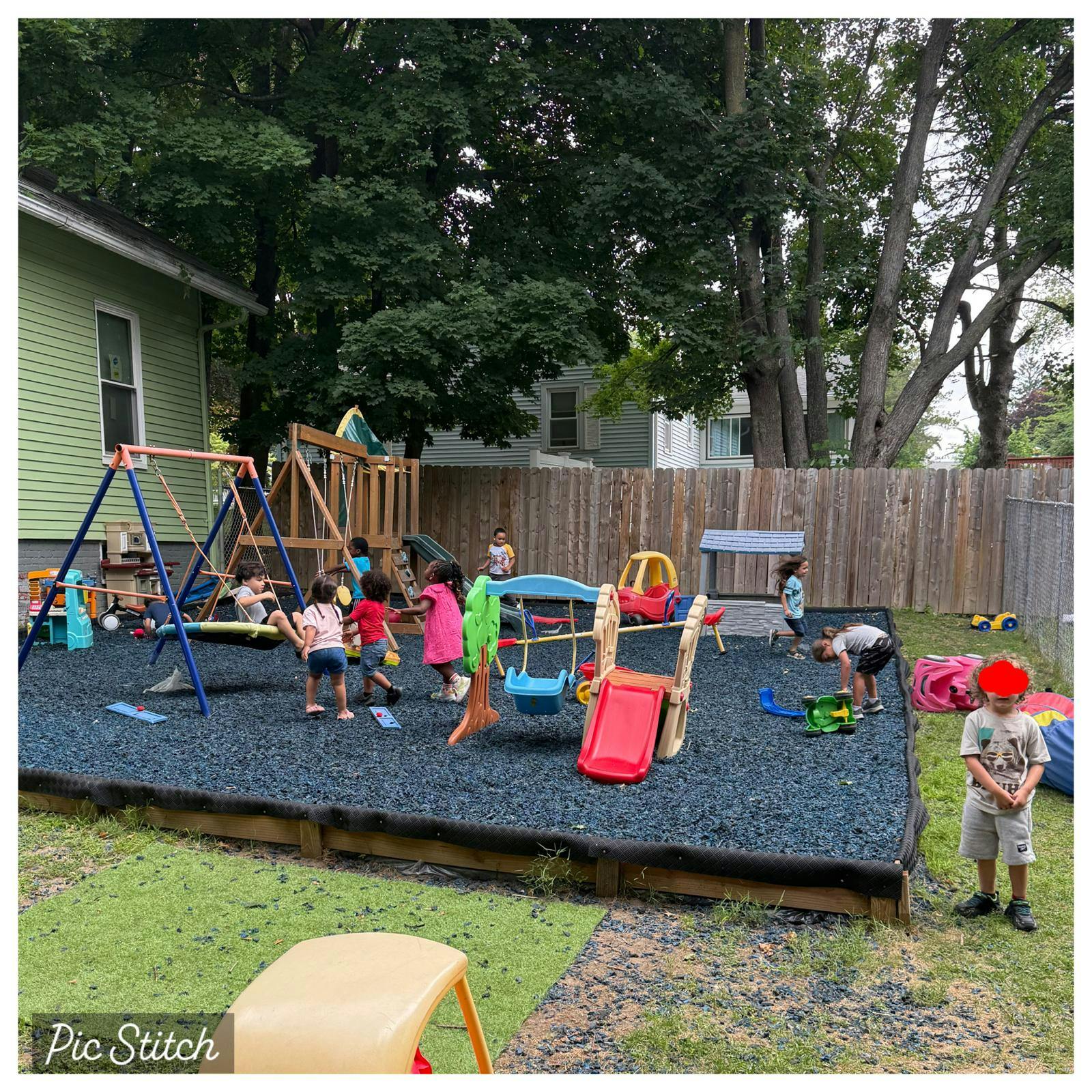 Group of children playing on playground equipment in a fenced backyard