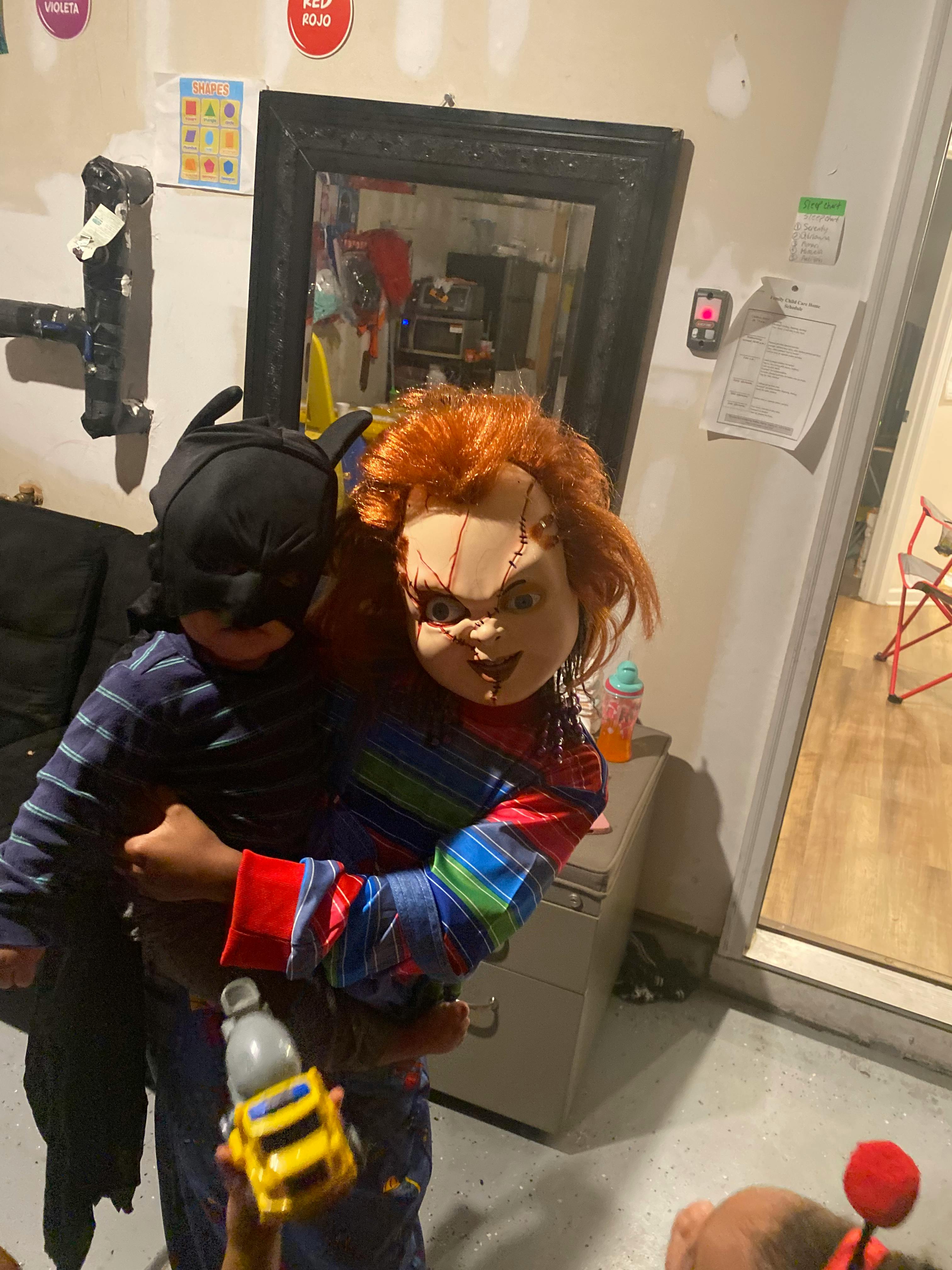 Child in Batman costume holding child in Chucky costume