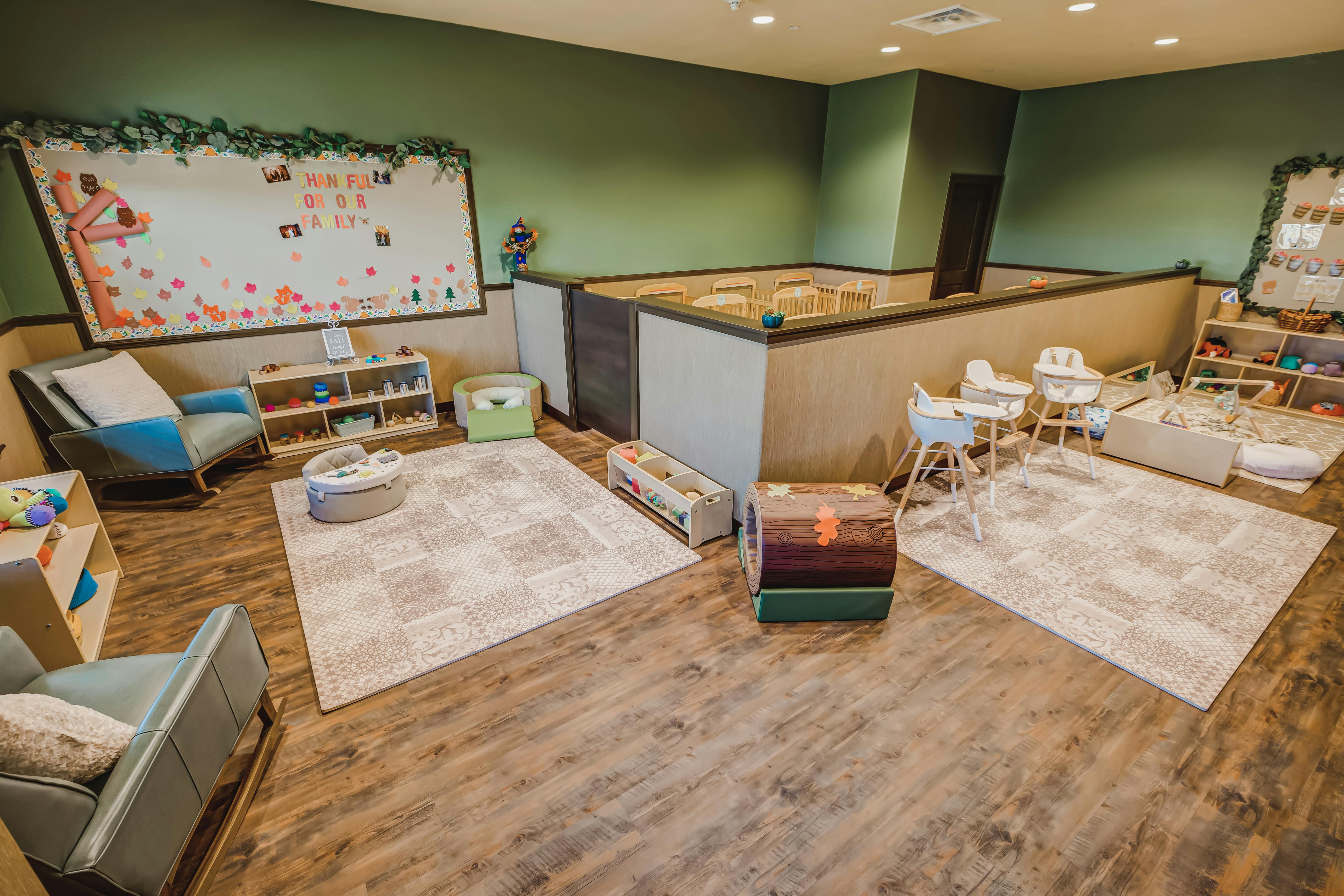 Playroom with rugs, chairs, and a low playpen