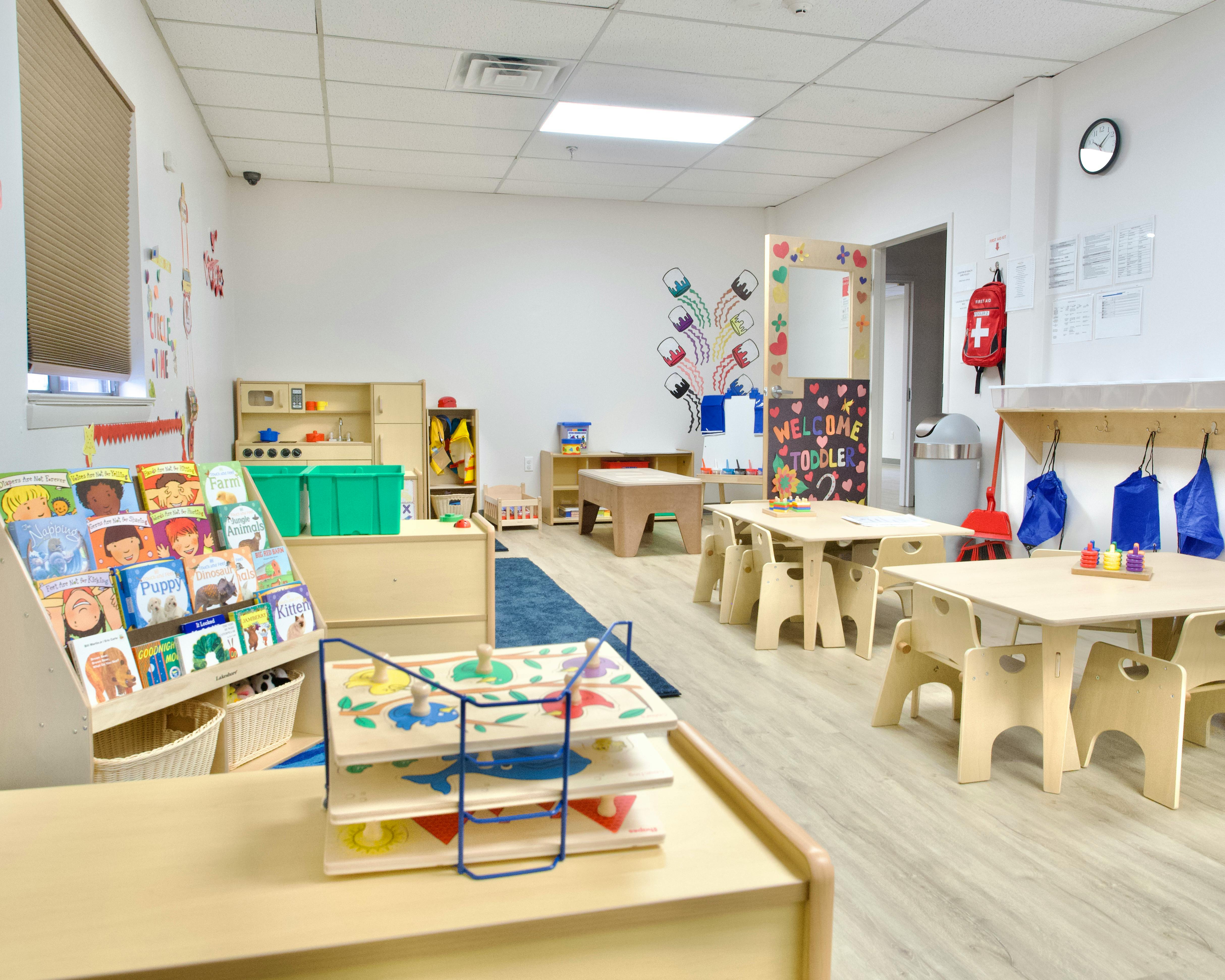 Classroom with small tables and chairs, bookshelves, and learning materials