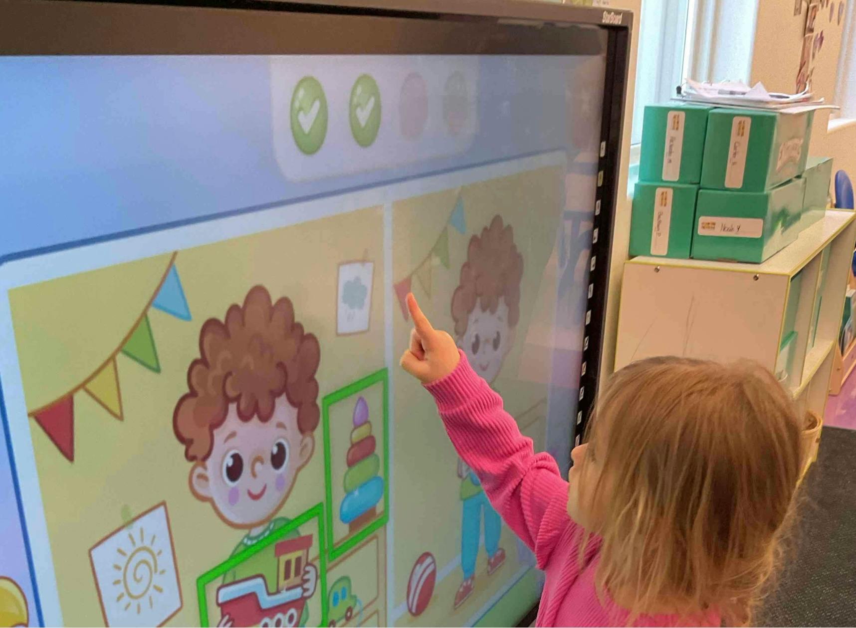 Child pointing at an interactive screen with cartoon images