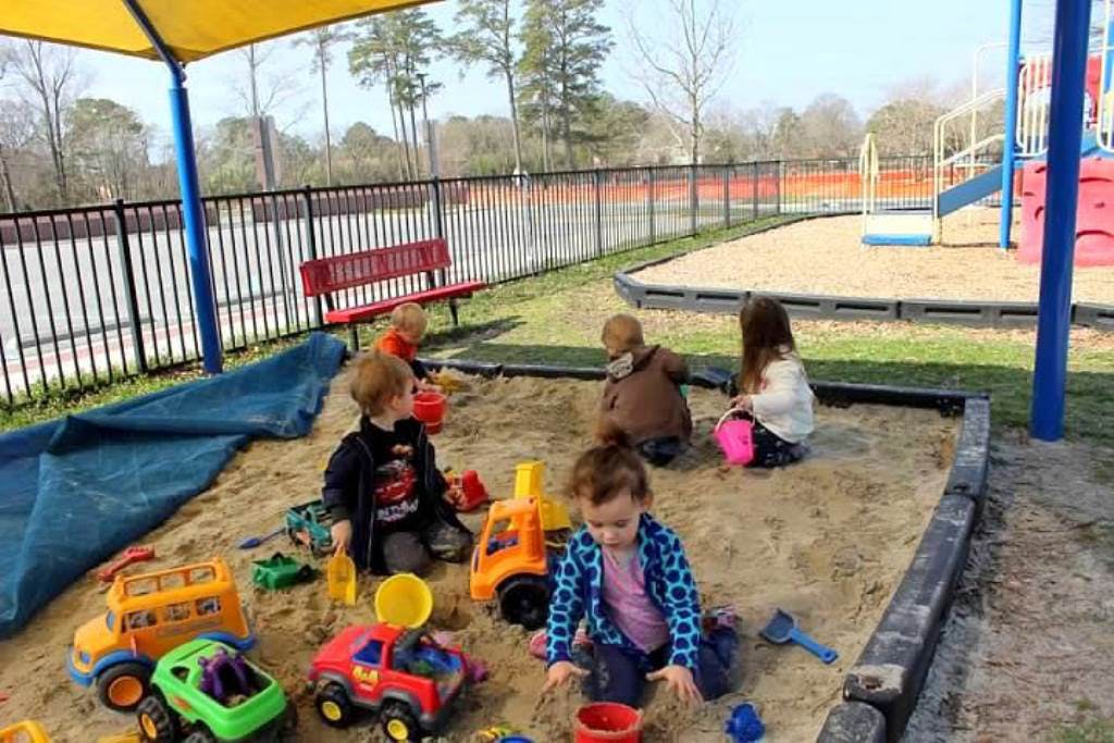 Children playing in a sandbox with toys