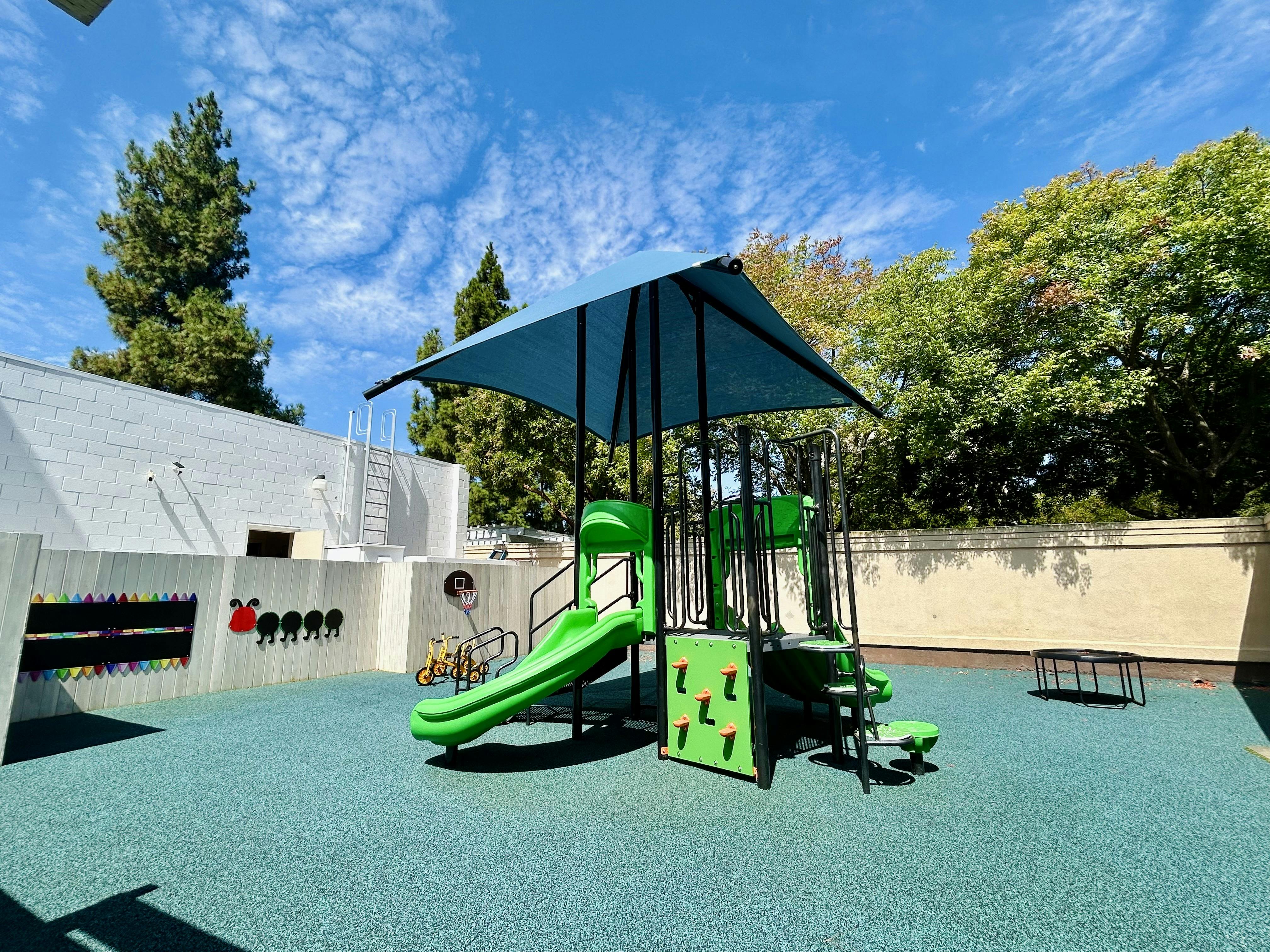 Playground structure with a slide and shade canopy in an outdoor play area