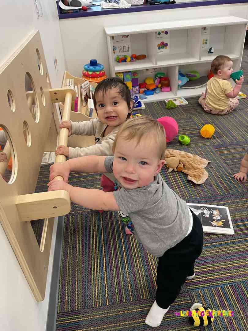 Two children holding onto a wooden play structure