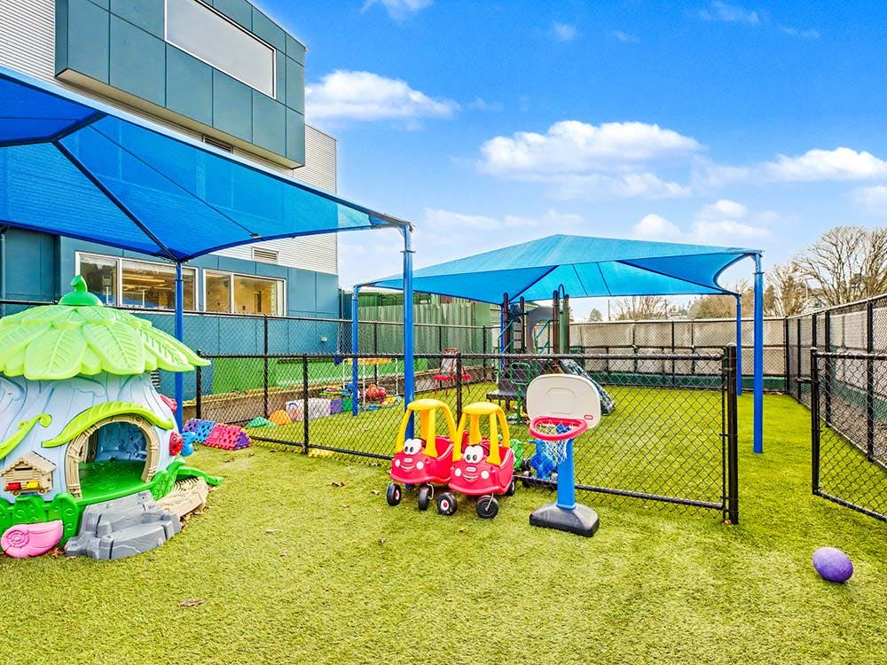 Outdoor playground with playhouses, toy cars, and basketball hoop