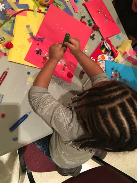 Child creating art with paper and glitter