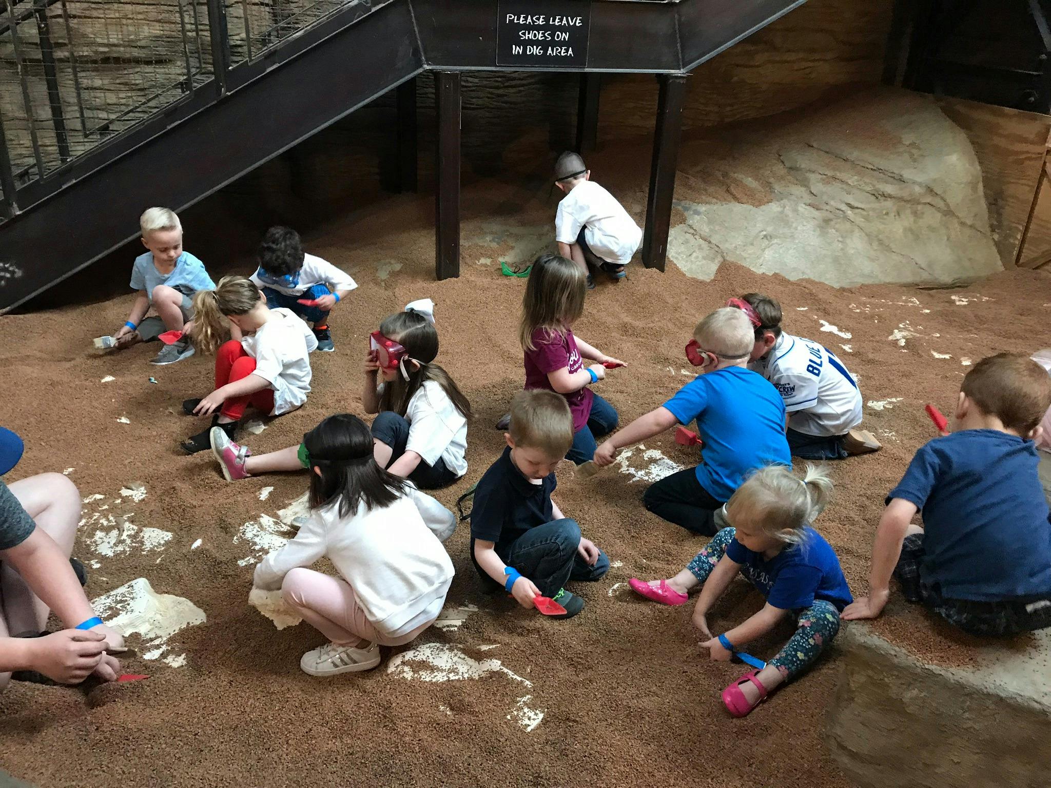 Many children playing in a large sandpit area