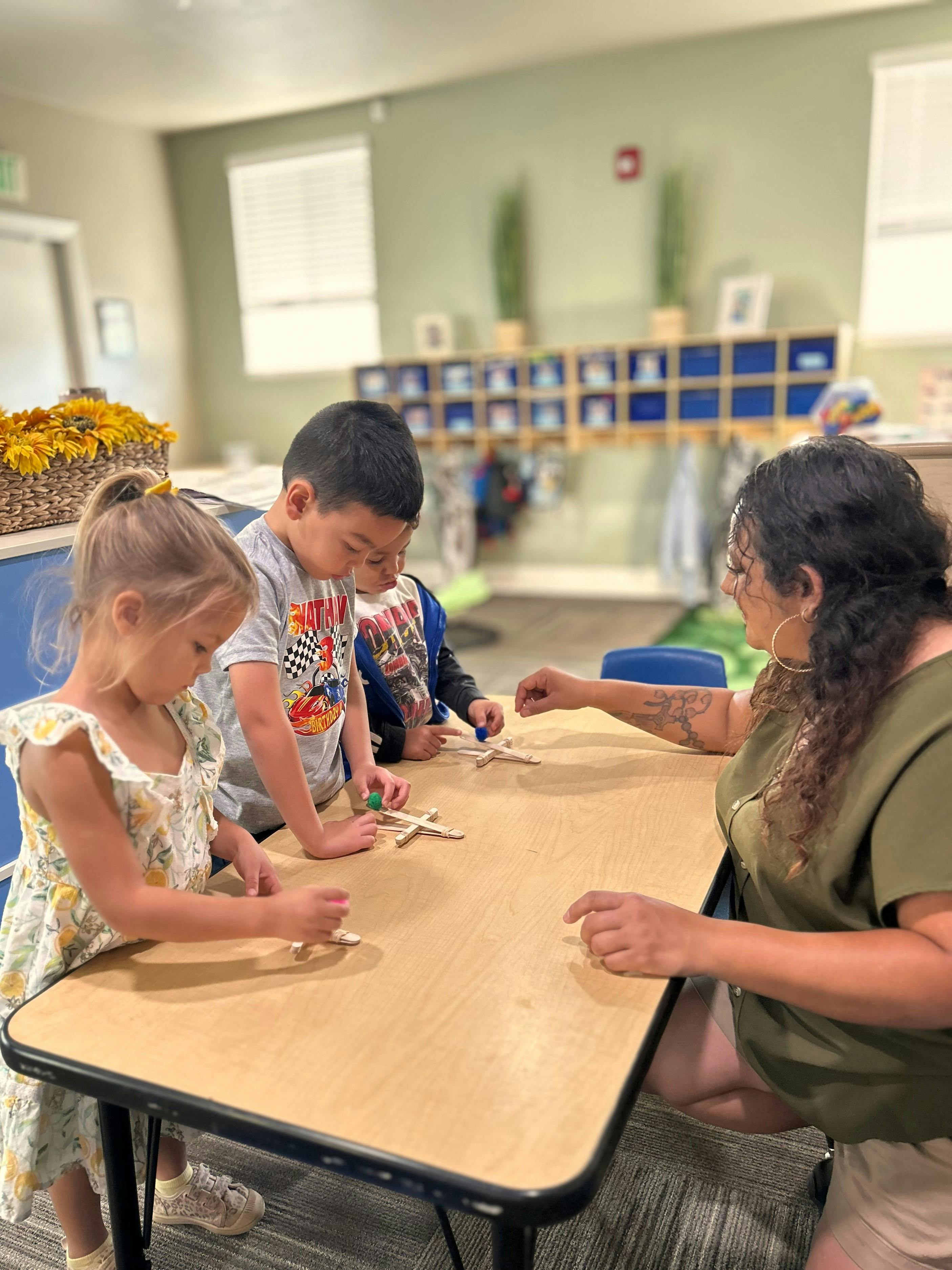 Adult and three children building with popsicle sticks at a table
