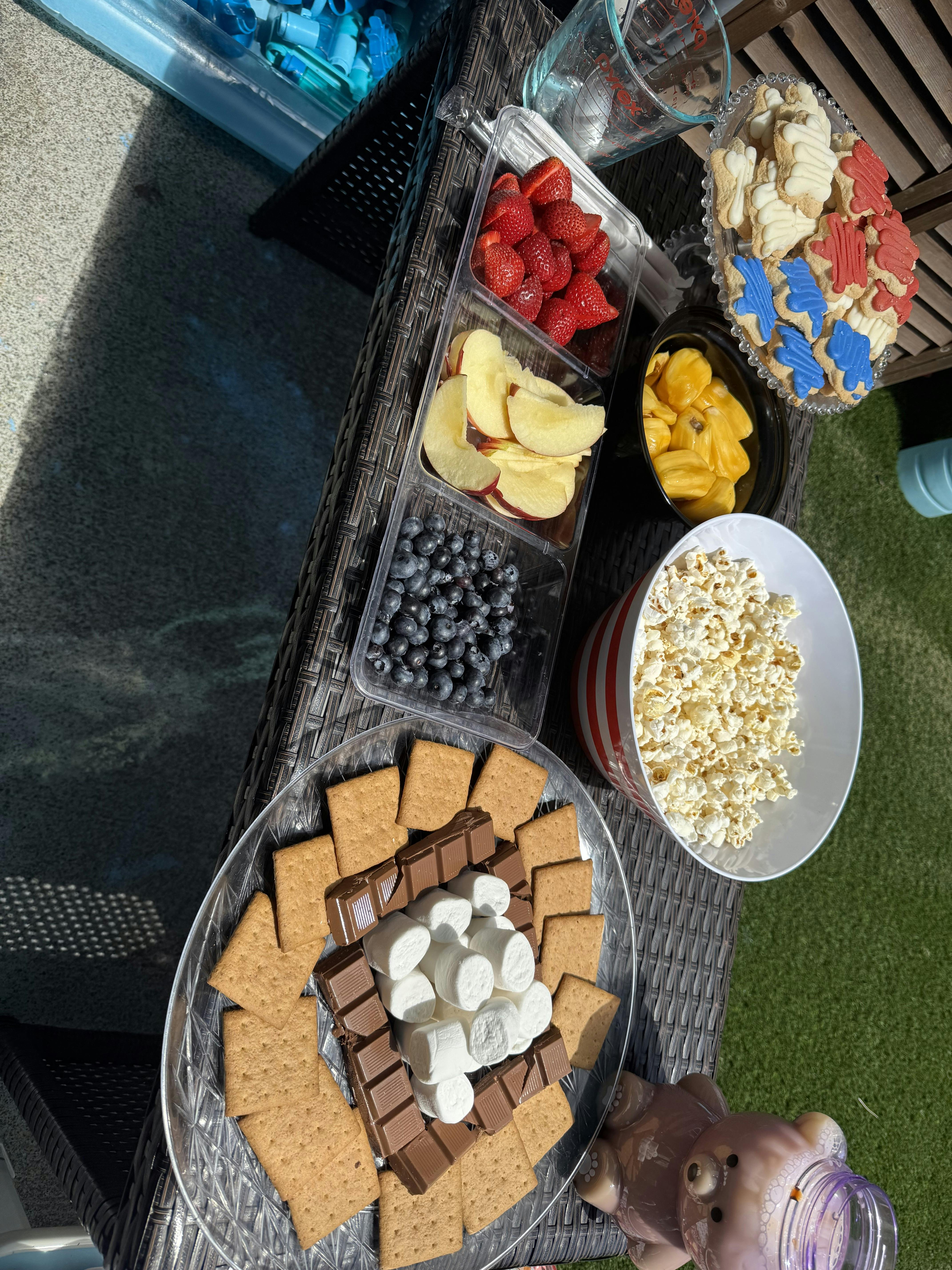 Table with fruit, popcorn, cookies, and s'mores ingredients