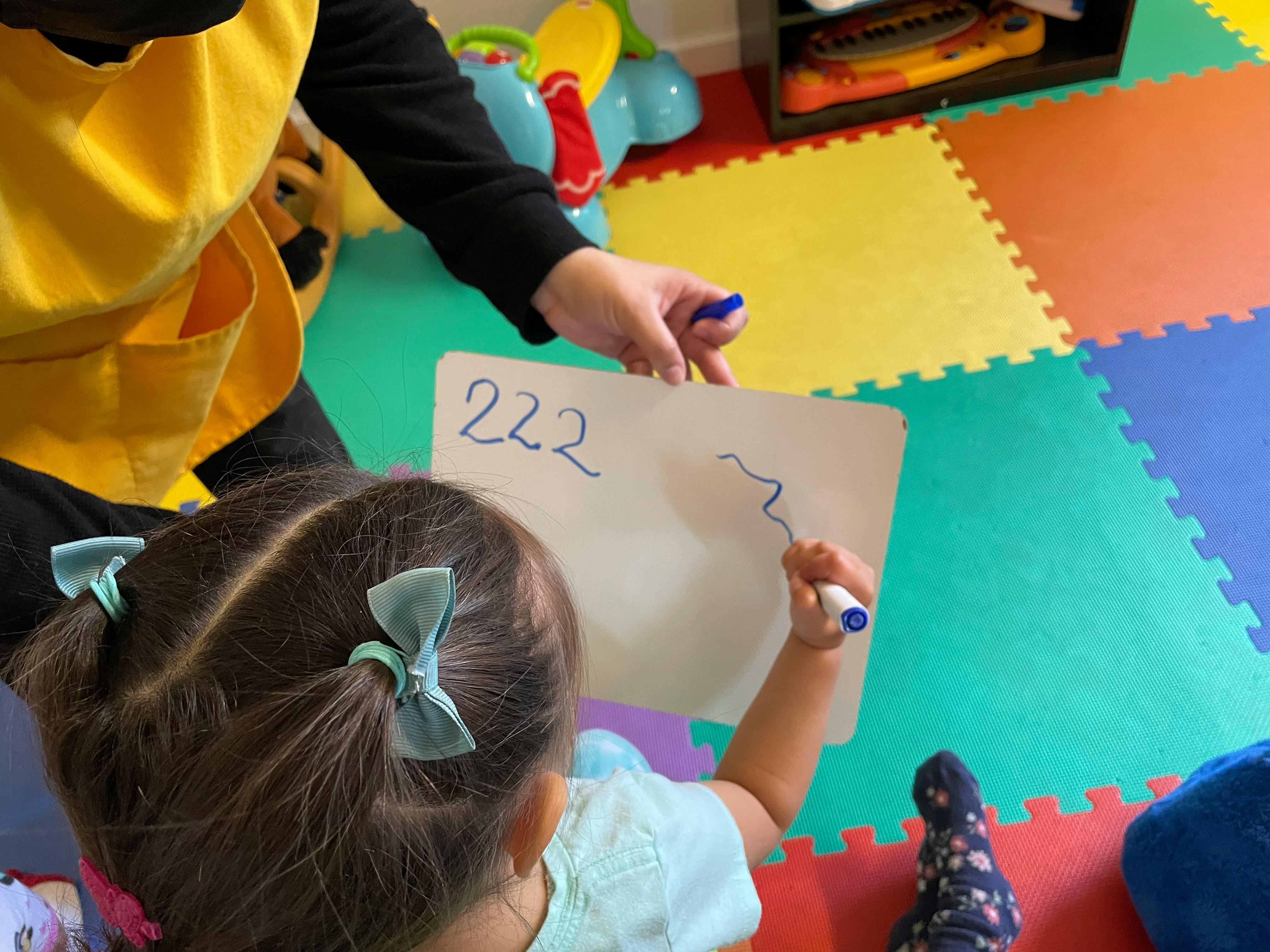 Person and child drawing on a whiteboard with "222" written on it