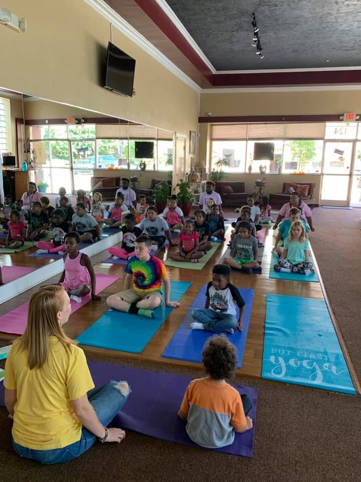 Adults and children sitting on yoga mats in a large room