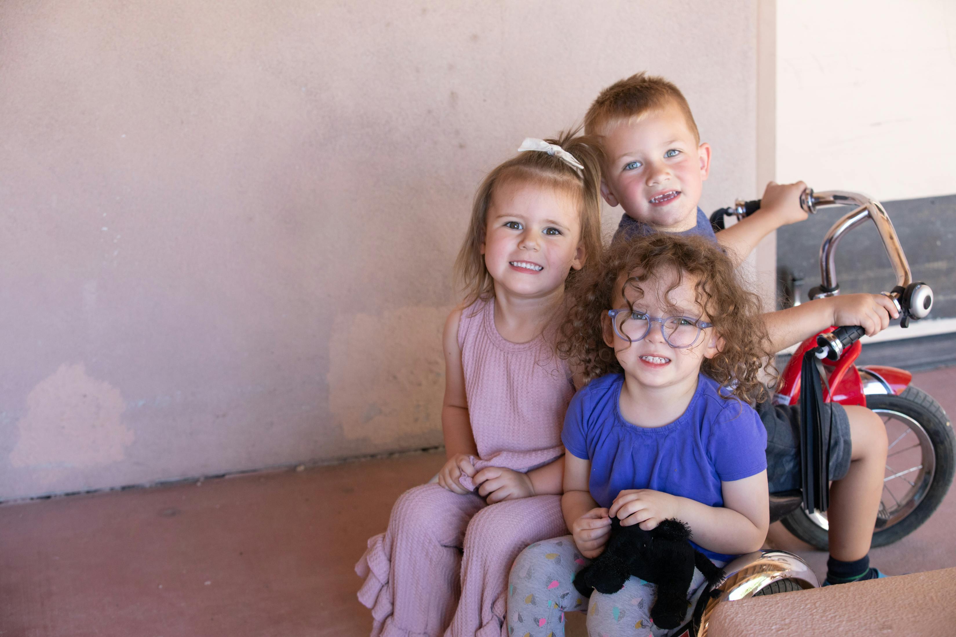 Three children posing together near a bicycle