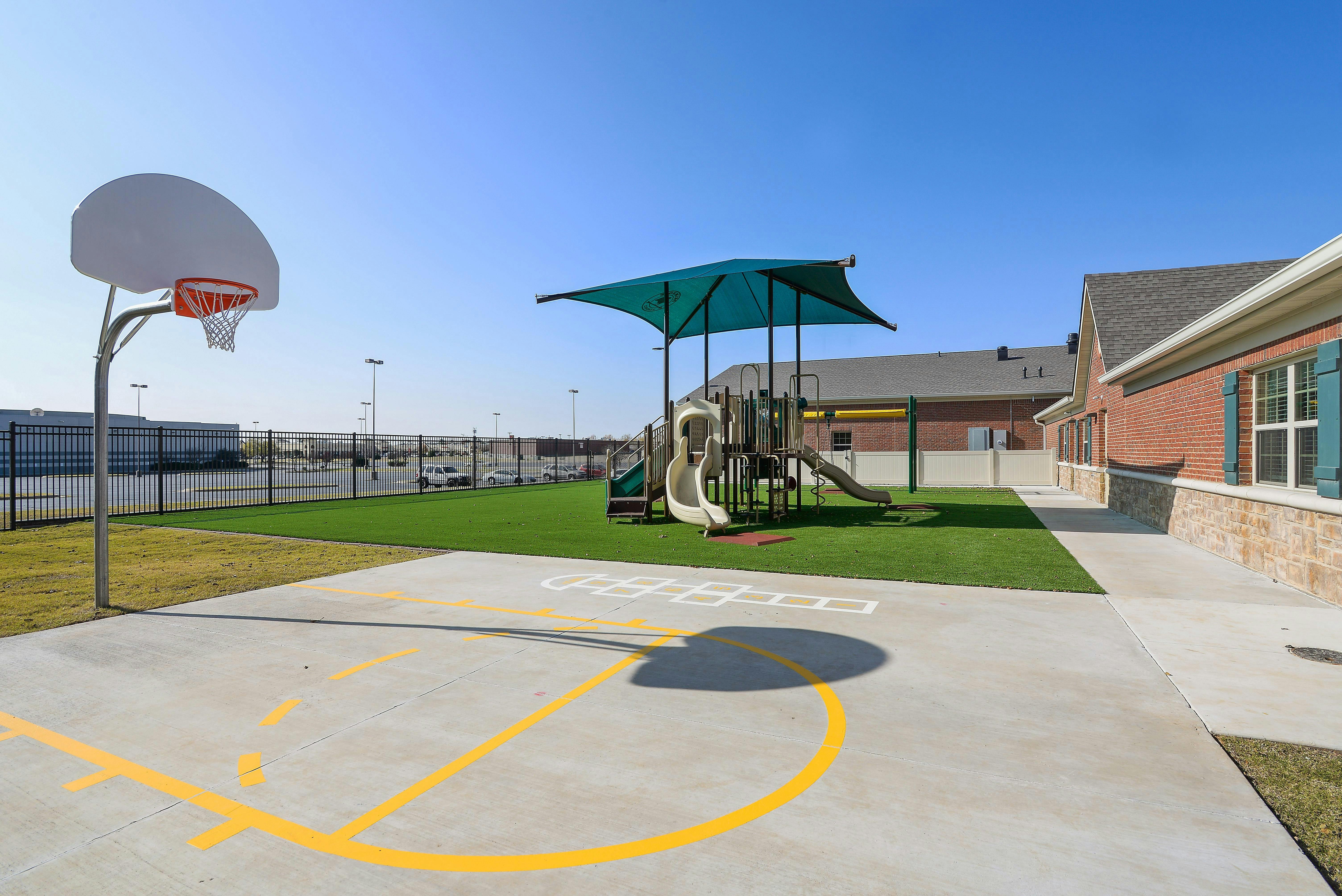 Outdoor basketball court and playground with slides and shade structure