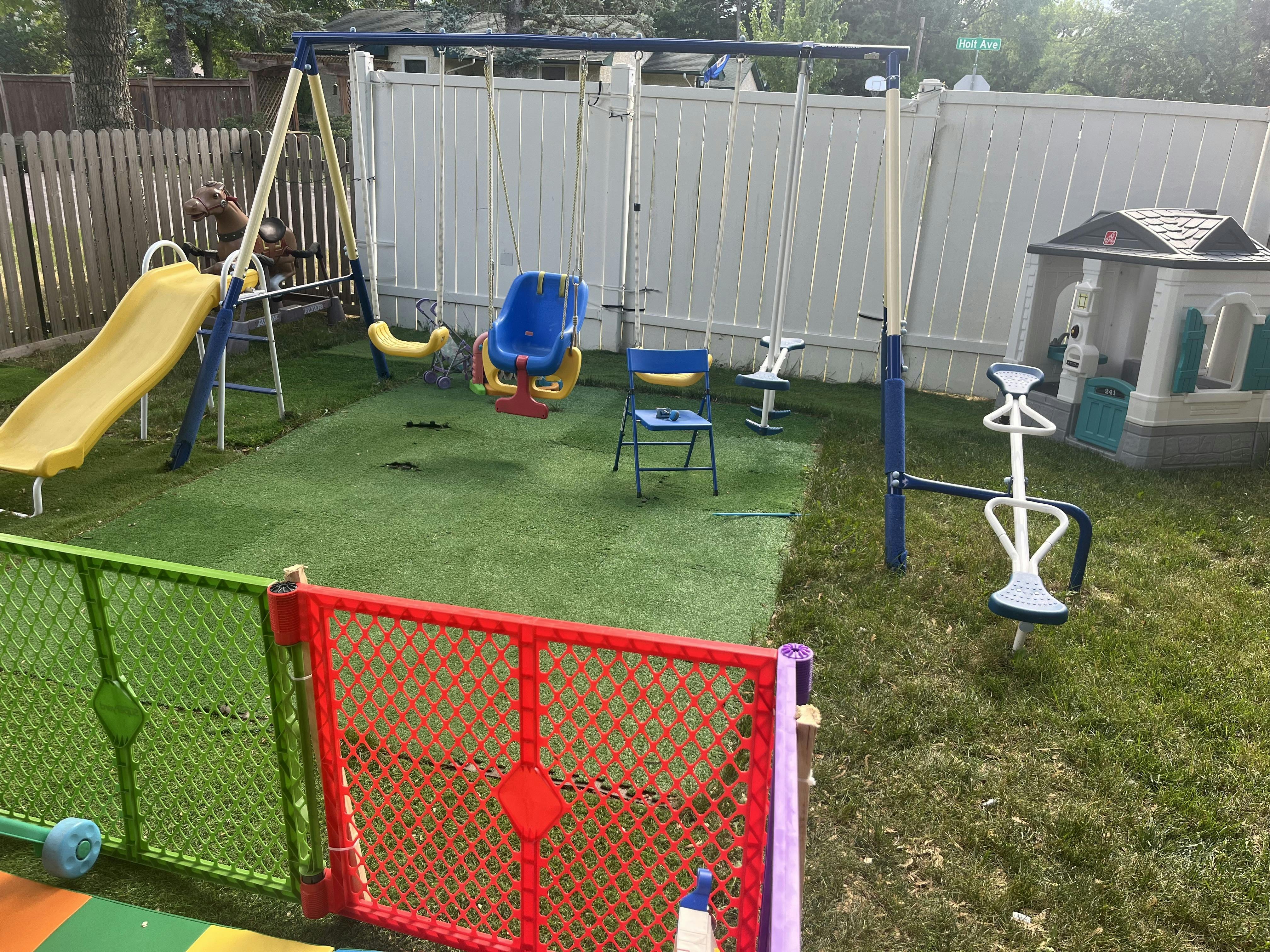 Backyard playground with swings, a slide, a playhouse, and a seesaw