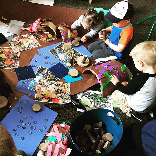 Three children playing with craft materials on the floor