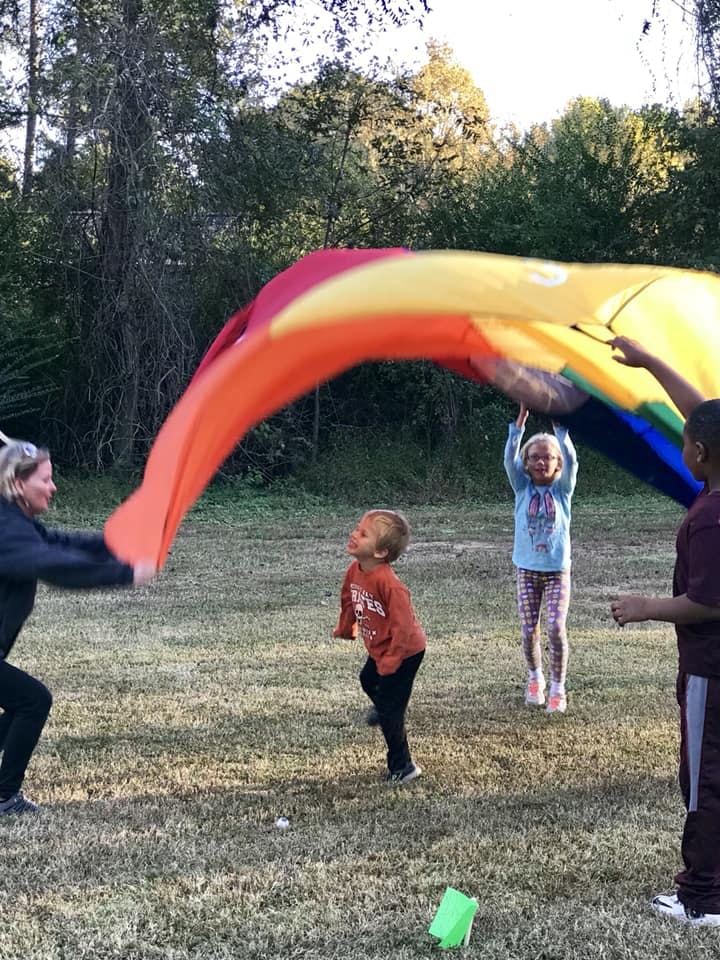 Adult and children playing with a colorful parachute outdoors
