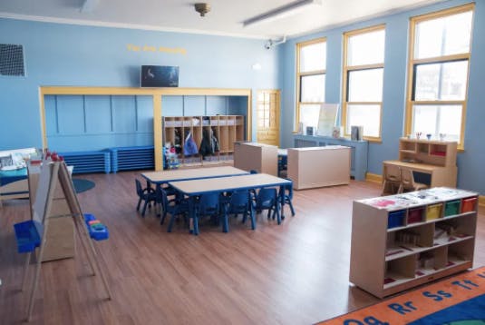 Classroom with small tables and chairs, storage units, and coat racks