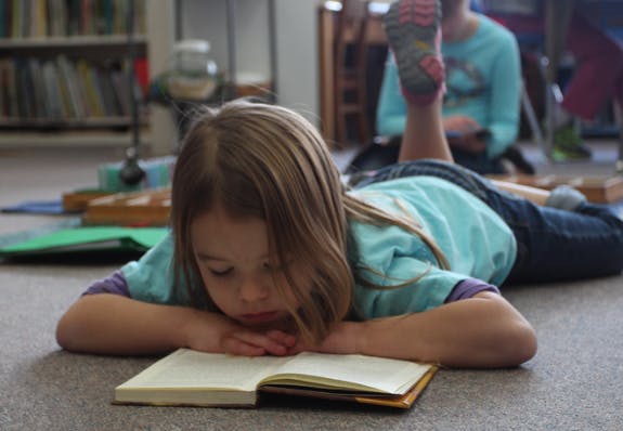 Child lying on floor reading a book