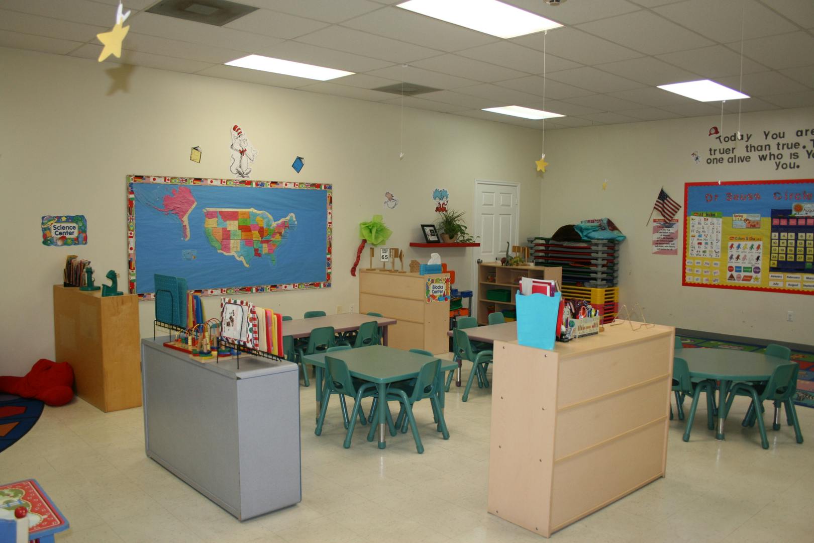 Empty classroom with small tables and chairs, map on bulletin board