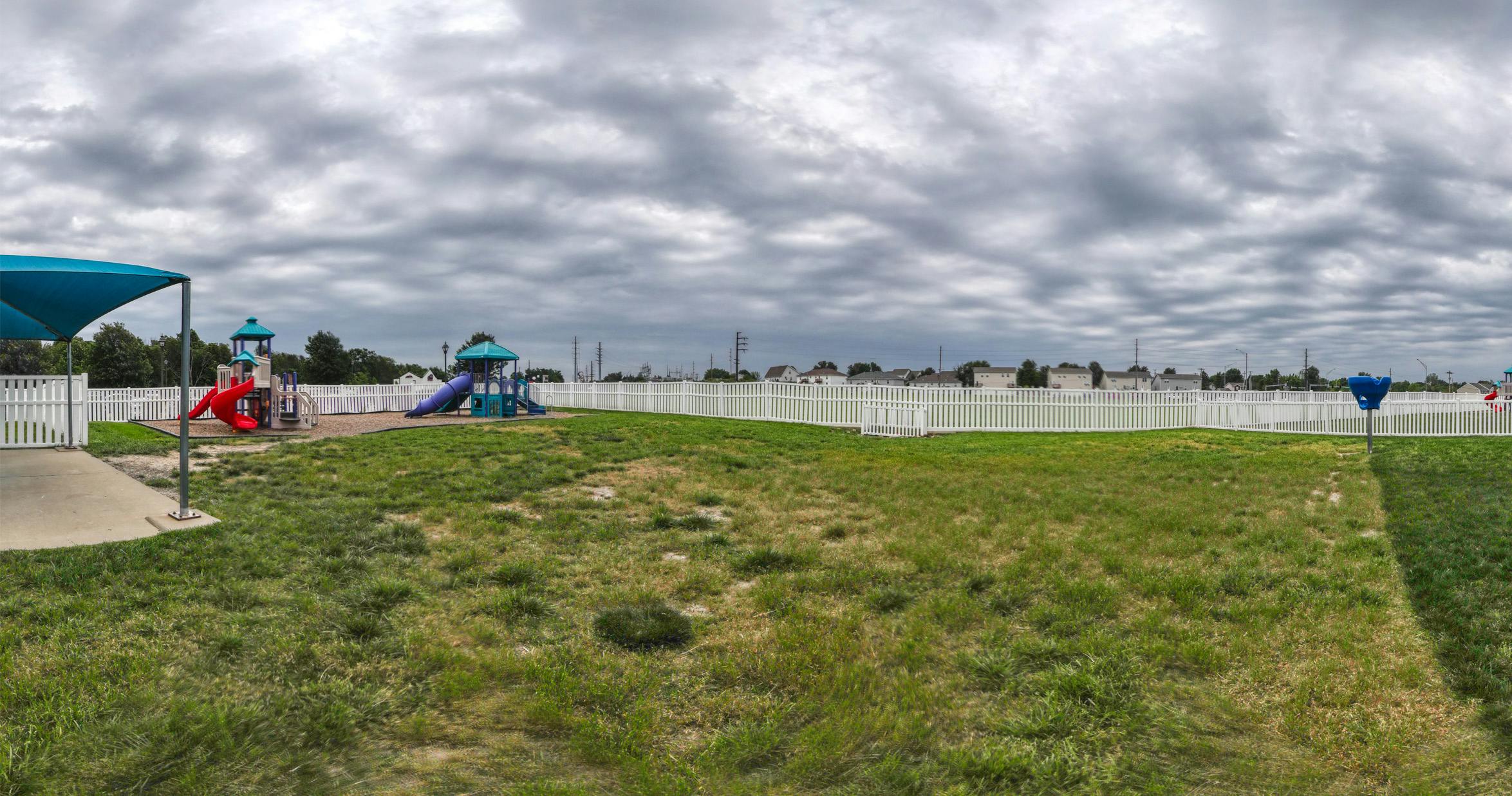 Playground with slides and play structures inside a white picket fence