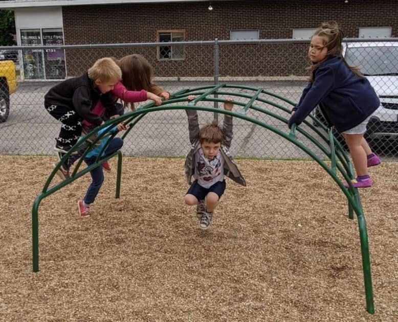 Children playing on a green climbing dome on a playground