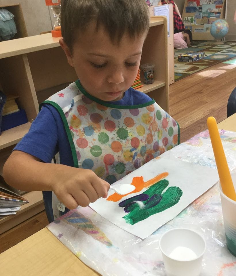 Child painting on paper with a spoon