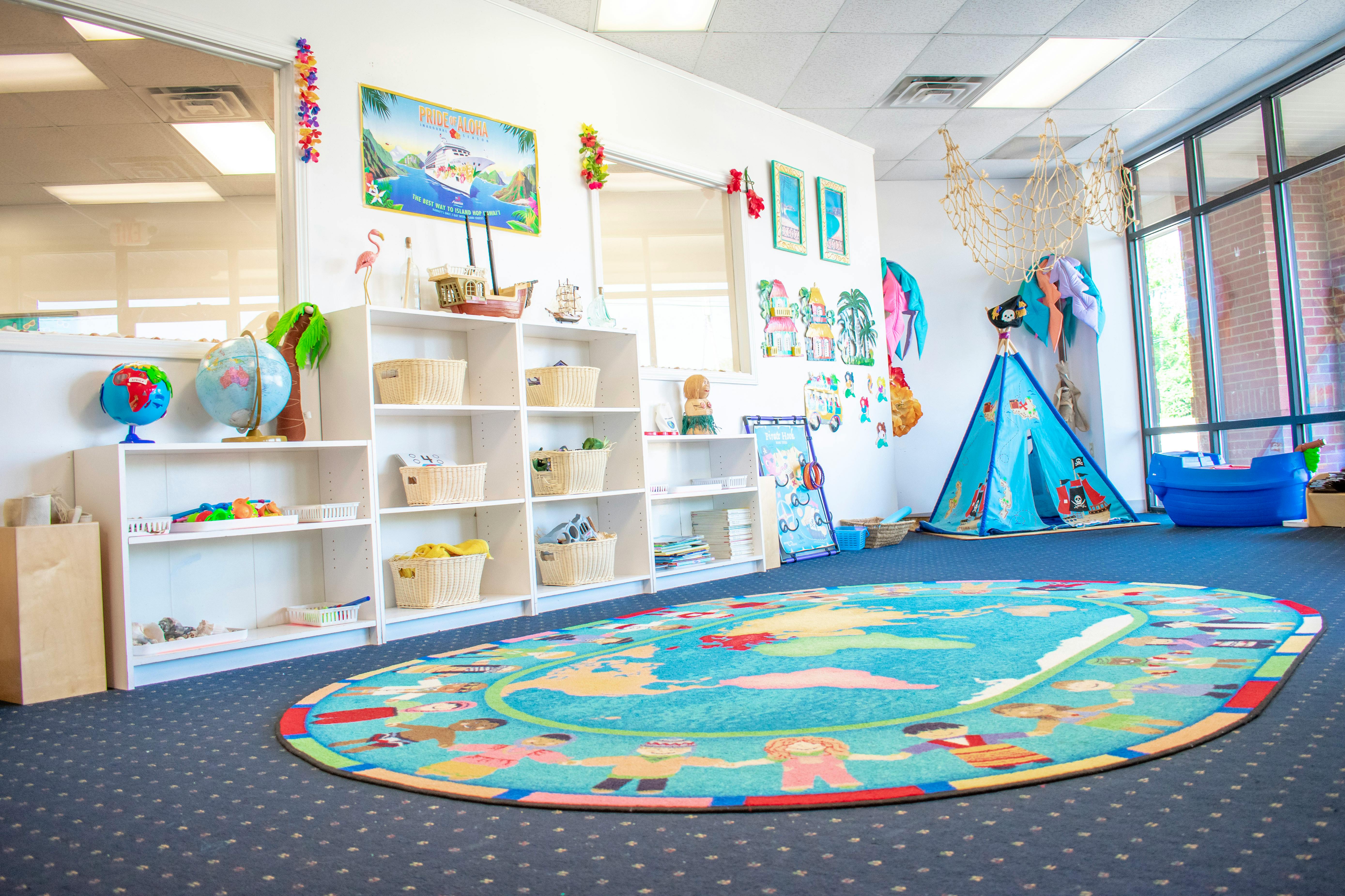 Playroom with shelves of toys, a blue tent, and a colorful rug