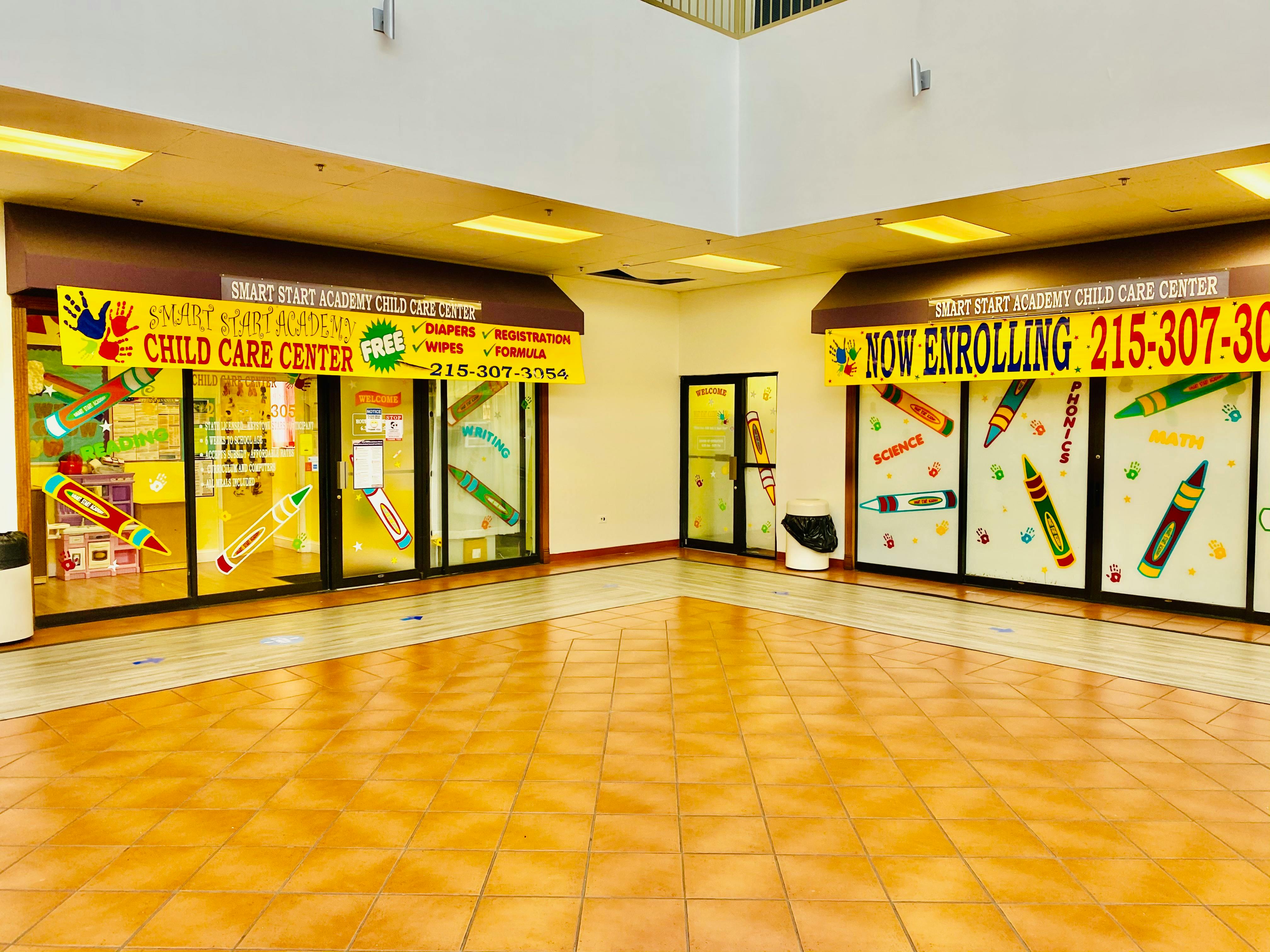 Child care center storefront with "NOW ENROLLING" banner