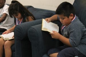 Children sitting on a couch reading books