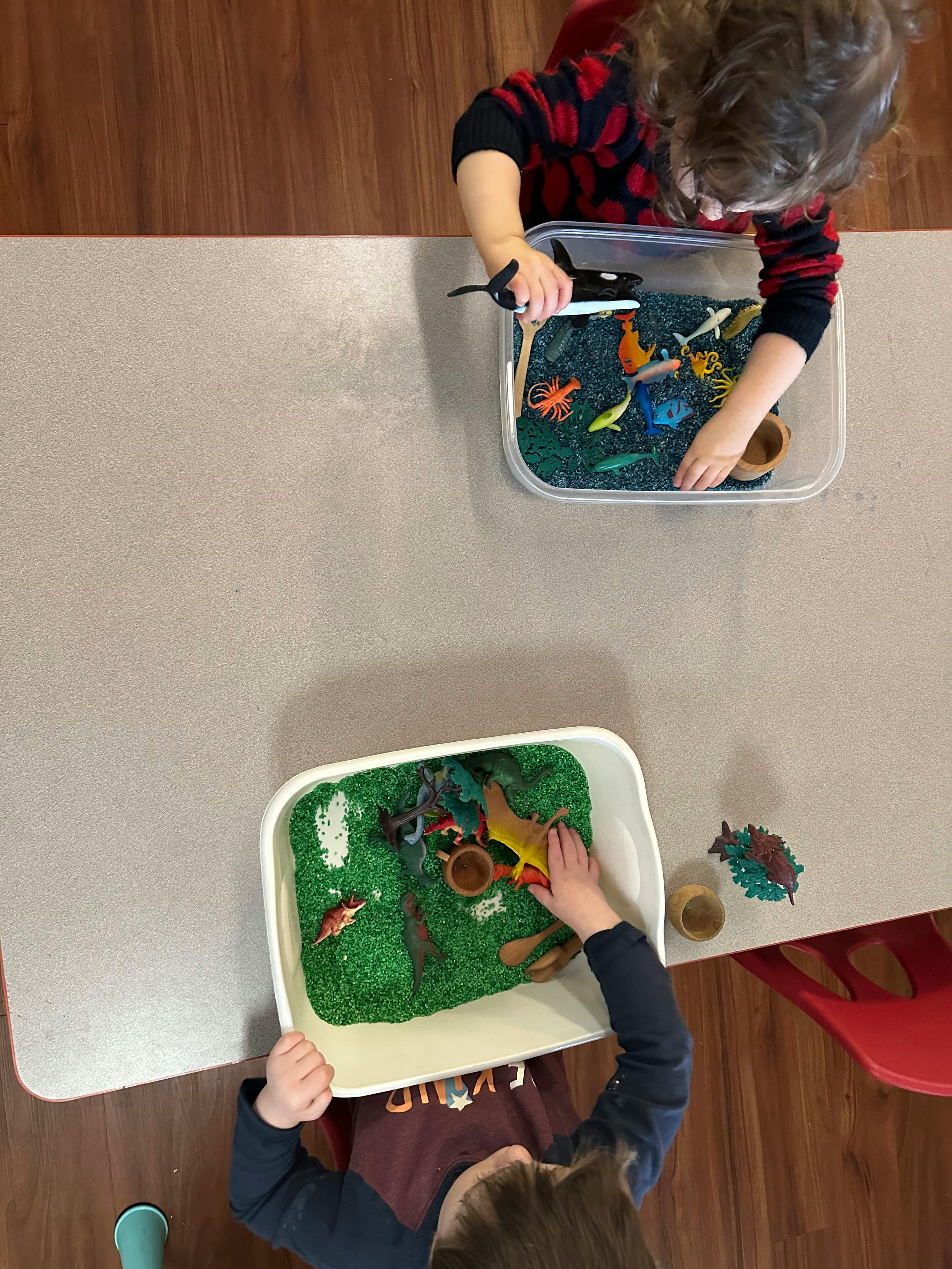 Two children playing with sensory bins filled with toys
