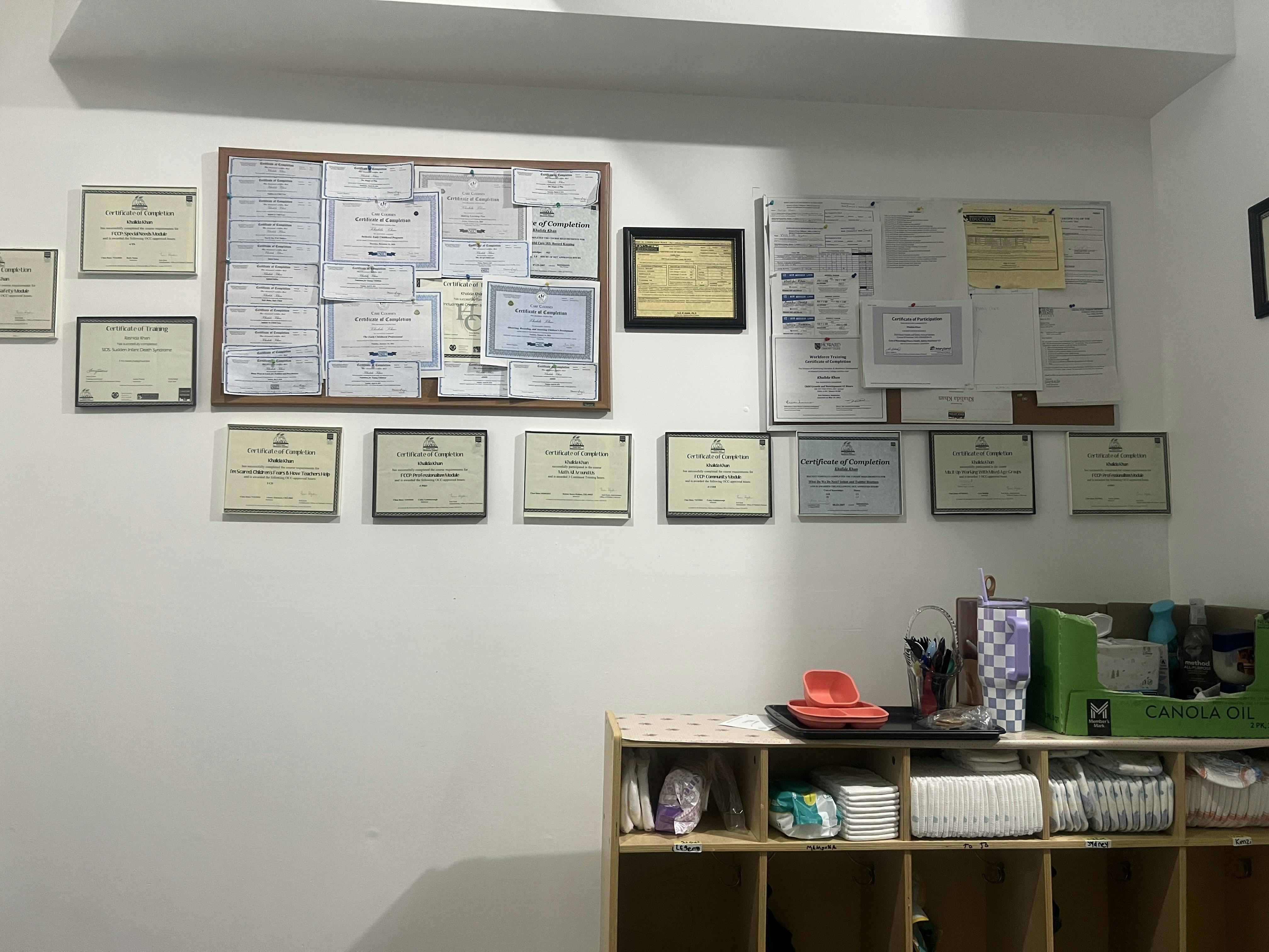 Wall with certificates of completion and training, and a cubby shelf with diapers