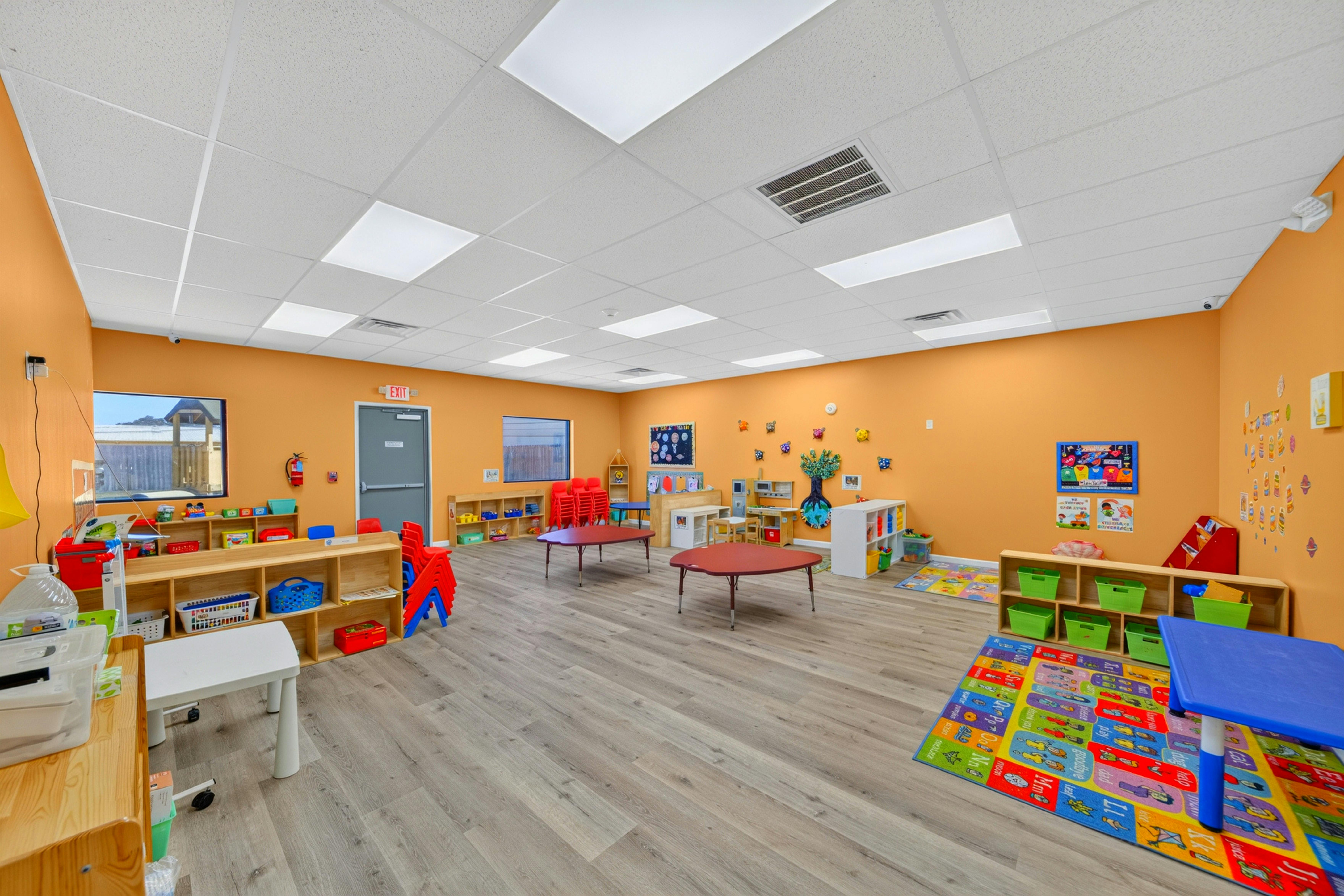 Empty preschool classroom with learning tables and educational wall decorations