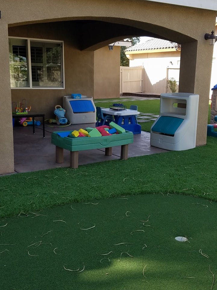 Outdoor play area with toys, a table, and artificial grass