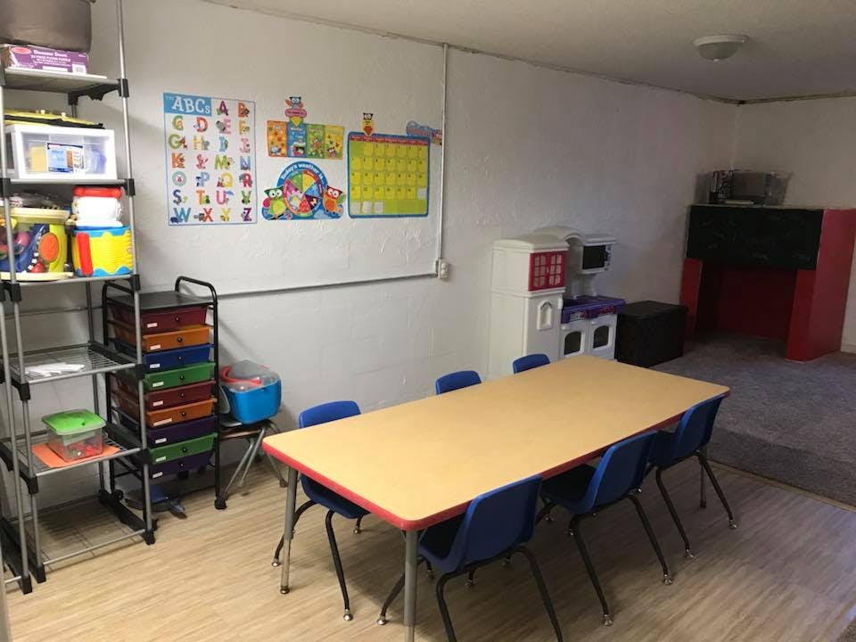 Classroom with a long table and chairs, shelves, and educational posters on the wall