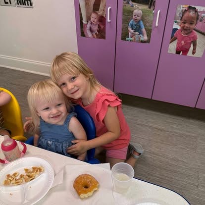 Two children sitting at a table with breakfast food