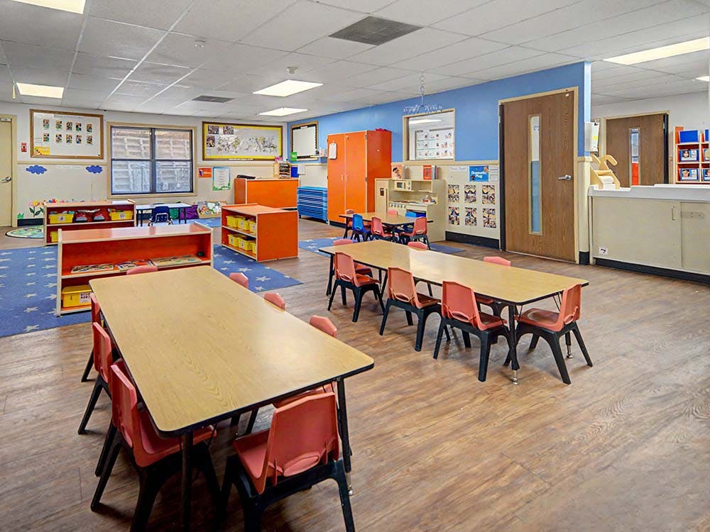 Empty classroom with tables, chairs, and colorful storage units