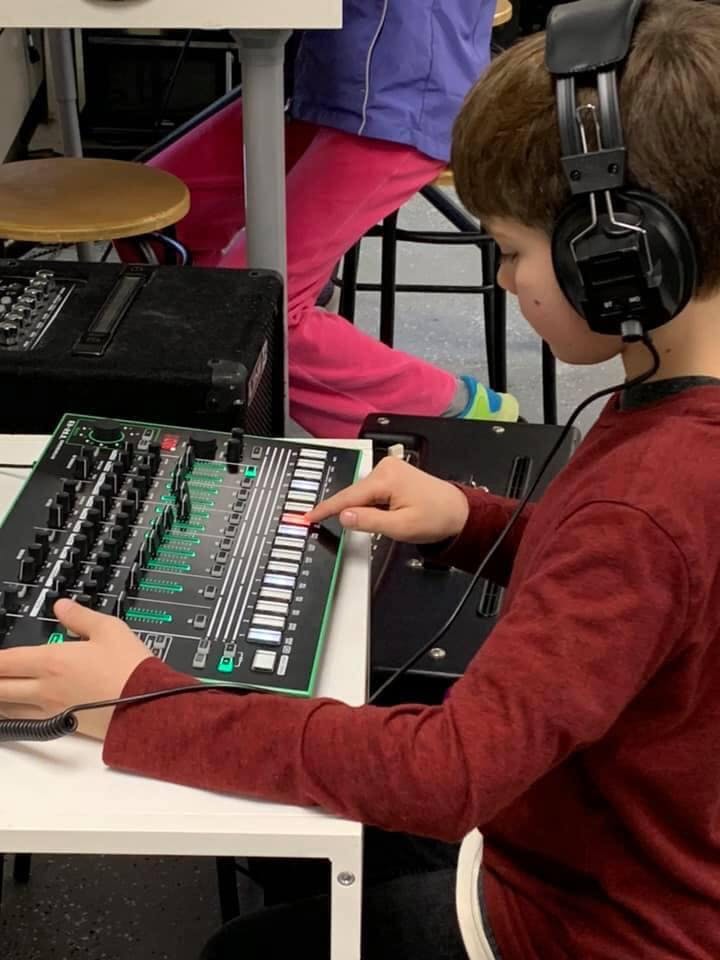 Child wearing headphones operating a sound mixer