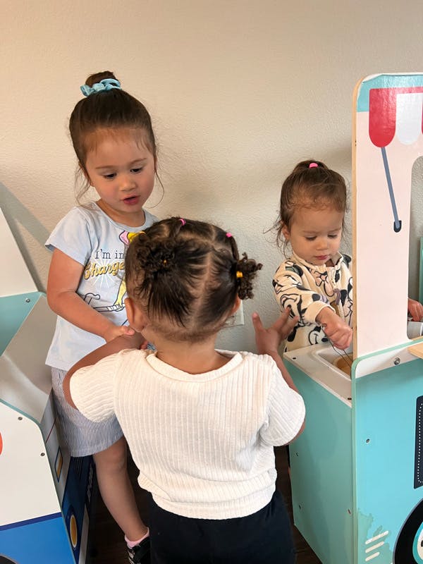 Three children playing with toy kitchen appliances