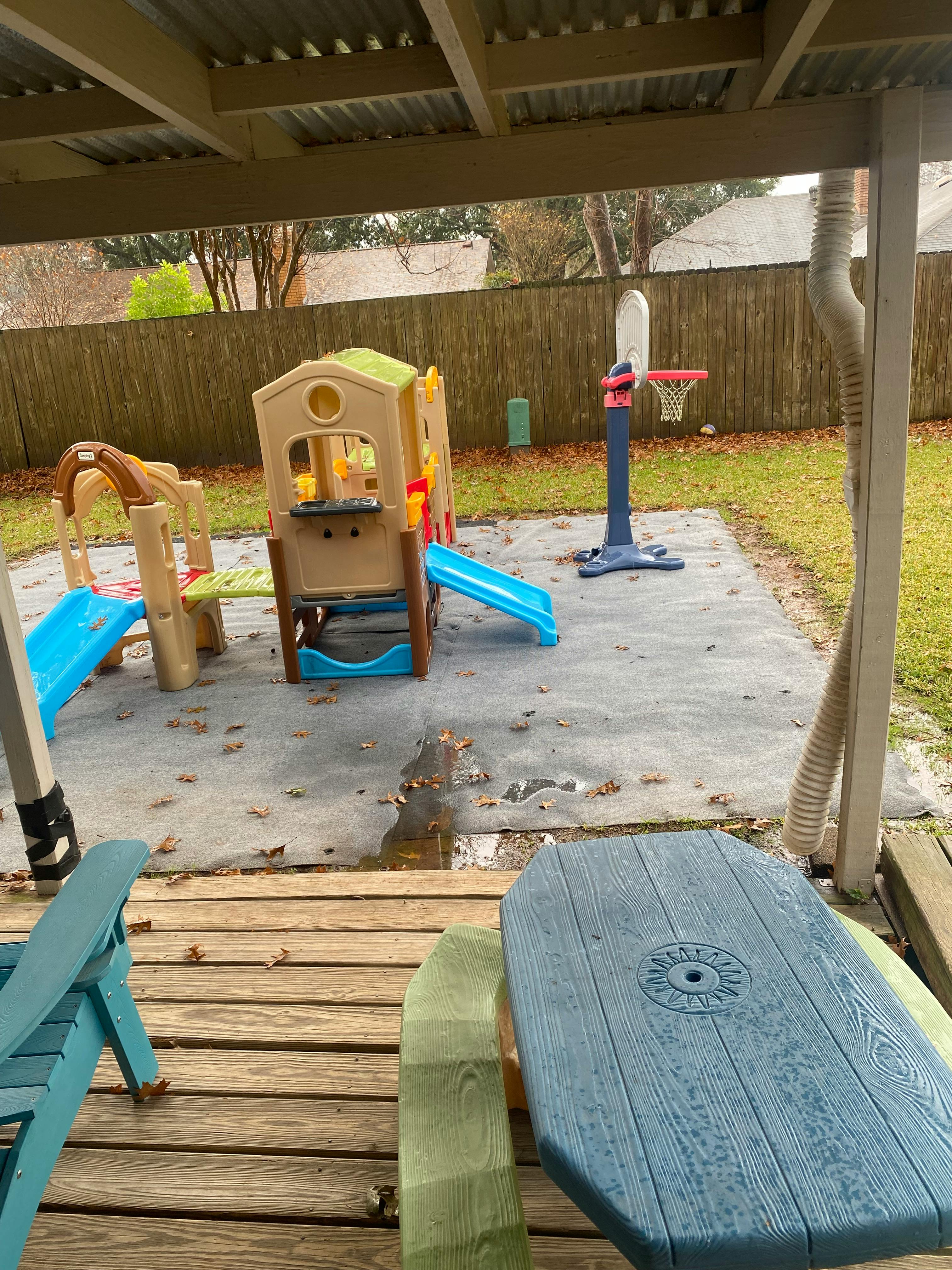 Outdoor play area with a playhouse, slides, and a basketball hoop