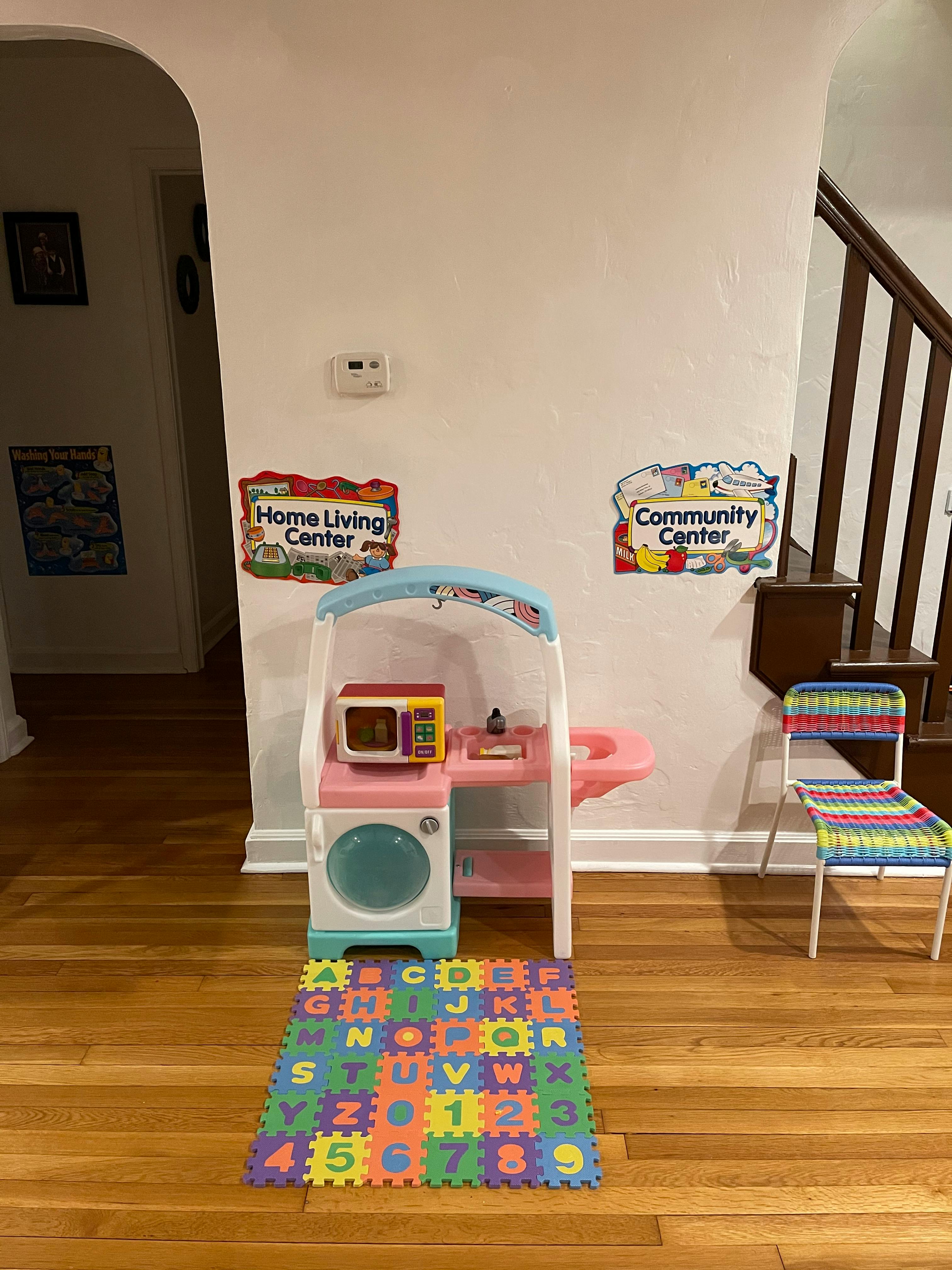 Child's play kitchen with a microwave, washer, and alphabet mat
